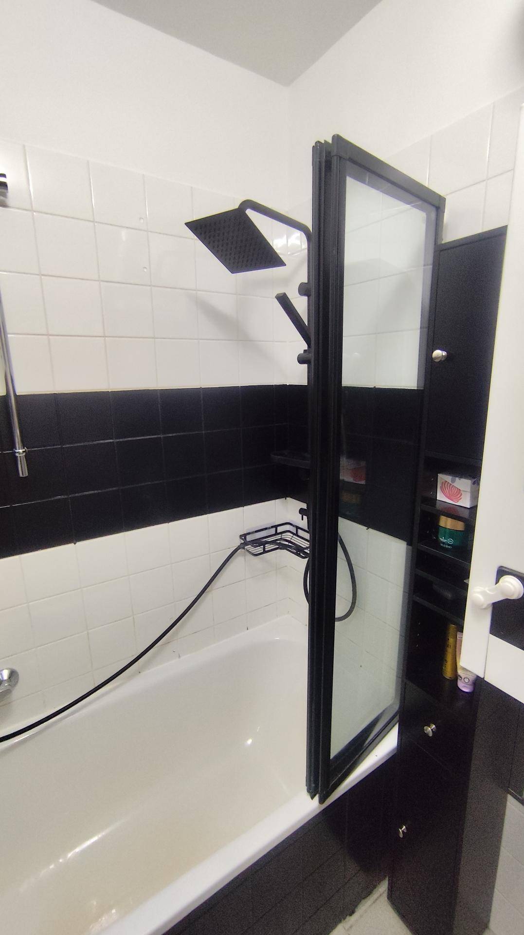 Badezimmer mit Badewanne, Duschabtrennung und Regendusche in Schwarz-Weiß-Design.