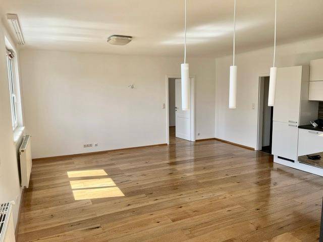 Heller Wohnbereich mit Holzboden, weißen Wänden und modernen Pendelleuchten.