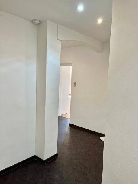 Heller Flur mit dunklem Boden und weißen Wänden, ausgestattet mit Deckenstrahlern.