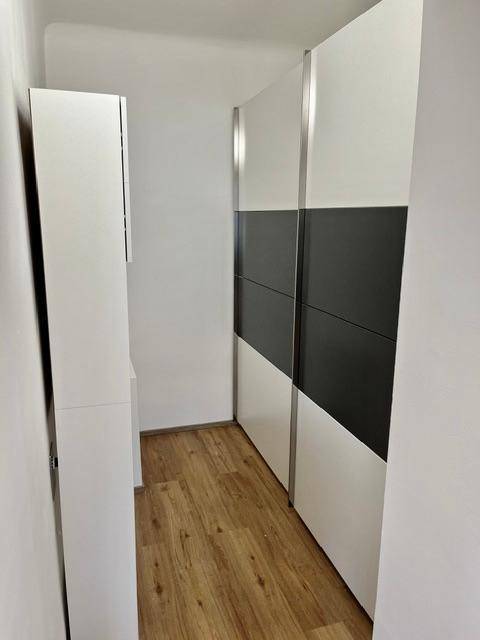 Schmaler Flur mit Laminatboden und einem modernen Einbauschrank in Weiß und Dunkelgrau.