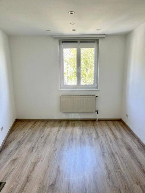 Helles Schlafzimmer mit hellem Laminatboden, Fenster und Deckenstrahlern.