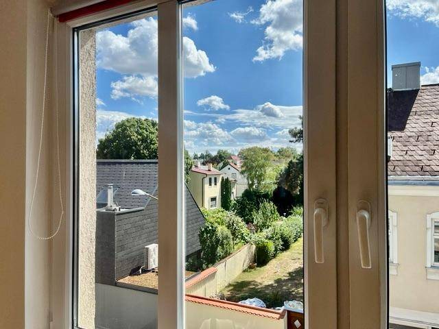Weitblick aus dem Fenster über Dächer, Bäume und umliegende Gebäude.