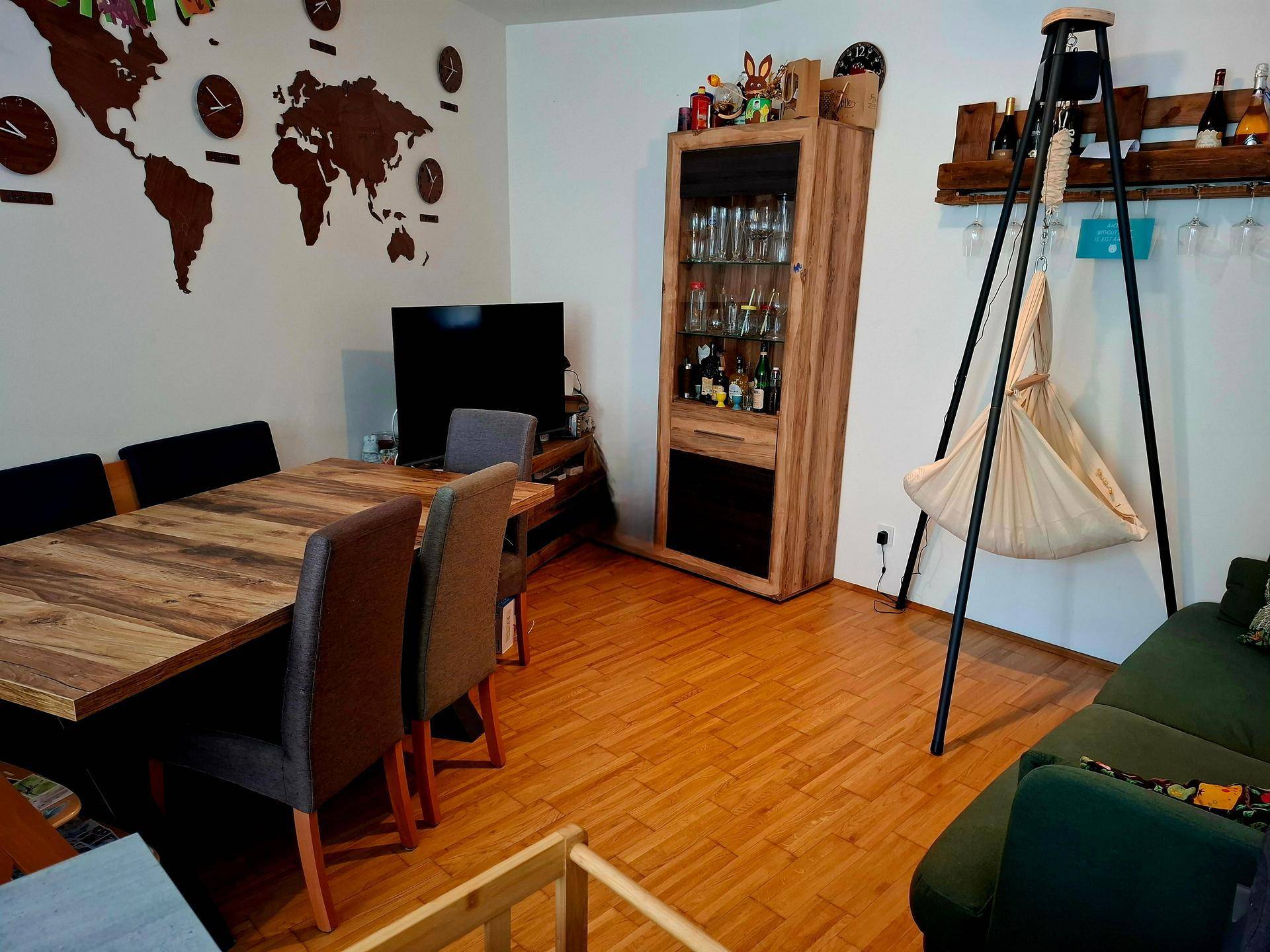 Gemütlicher Wohn-Essbereich mit Holzboden, Esstisch und Sofa, dekoriert mit Weltkarte.