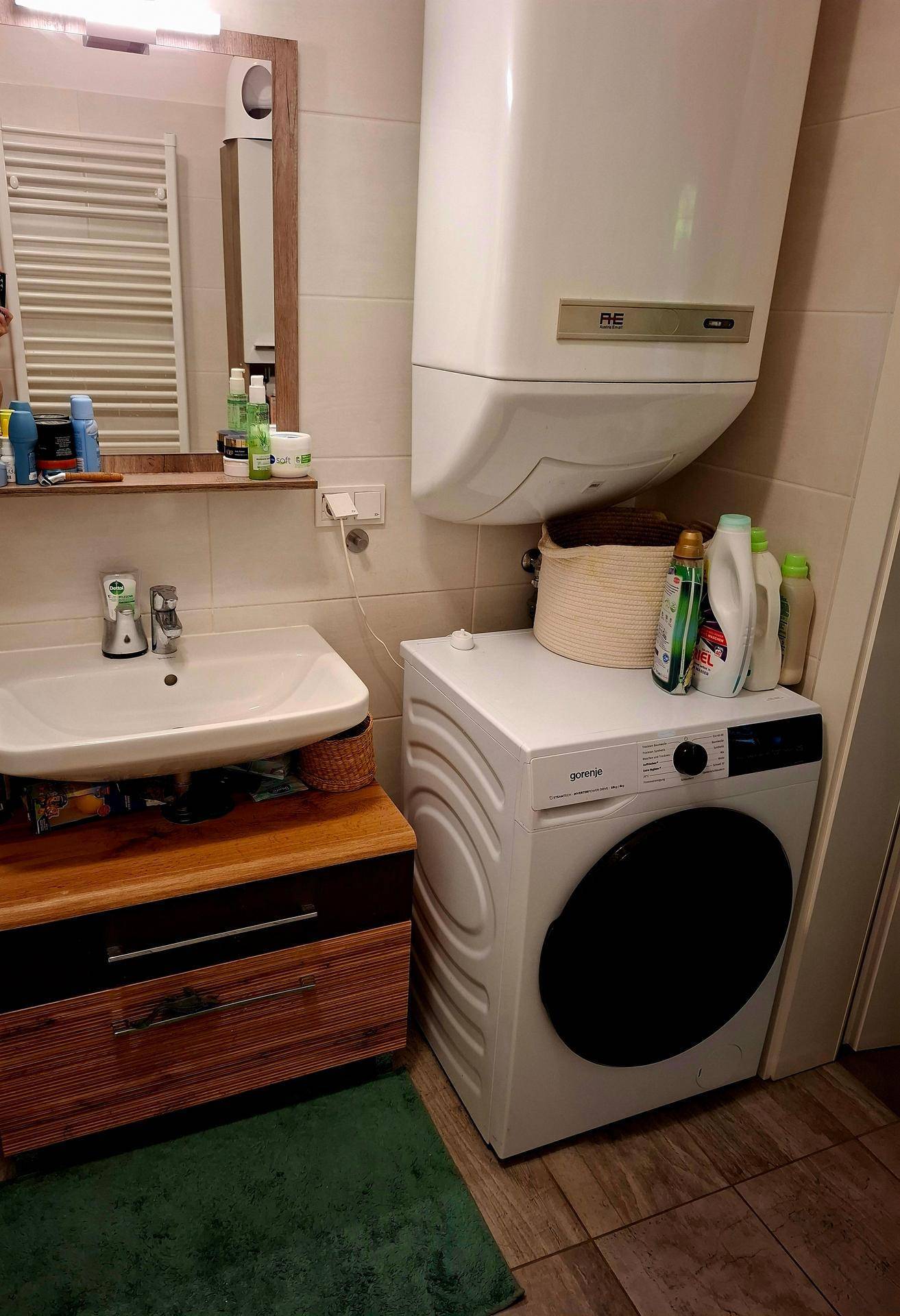 Badezimmer mit Waschbecken, Spiegelschrank und Waschmaschine, funktional eingerichtet.