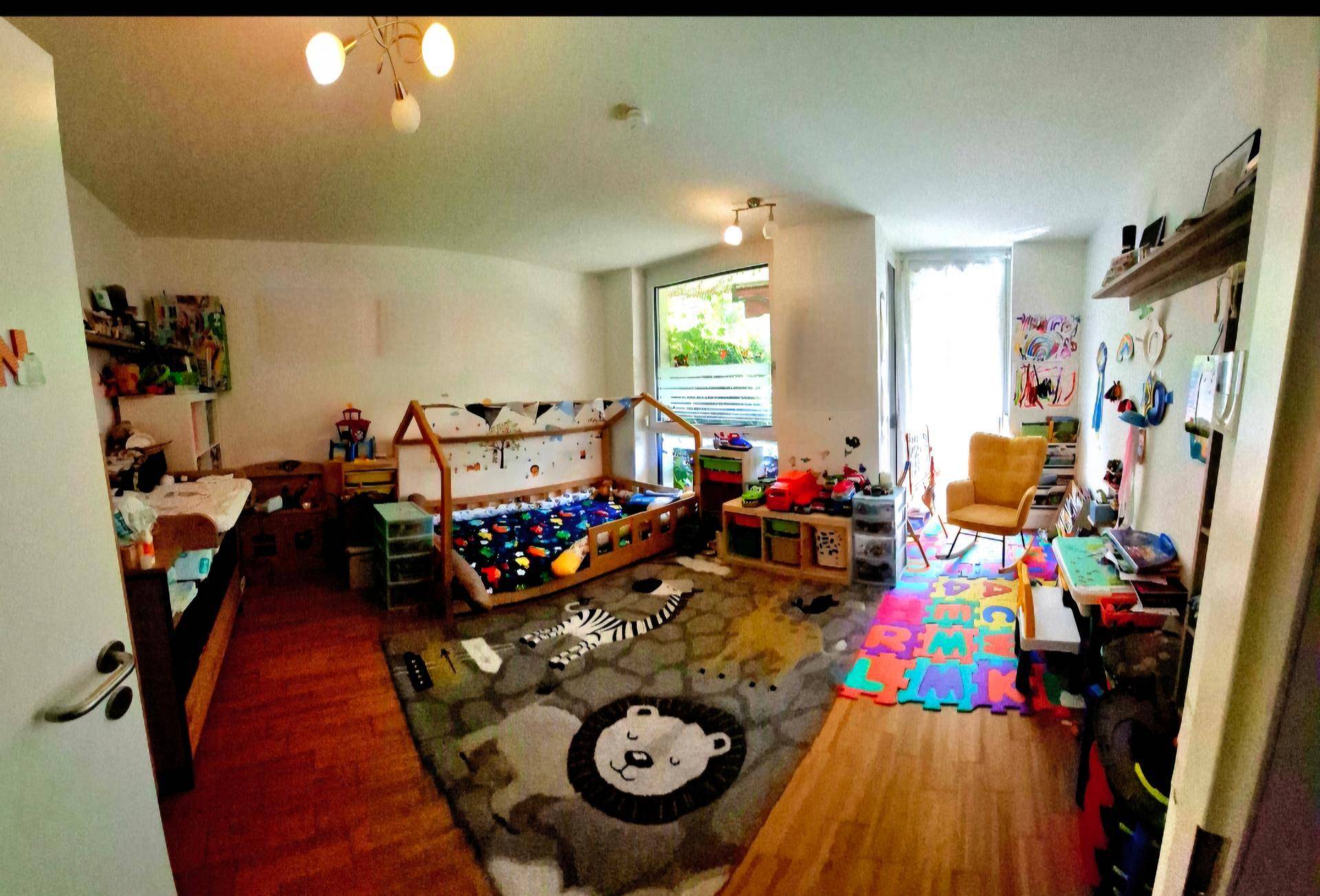 Farbenfrohes Kinderzimmer mit Holzboden und großem Fenster, hell und spielerisch eingerichtet.