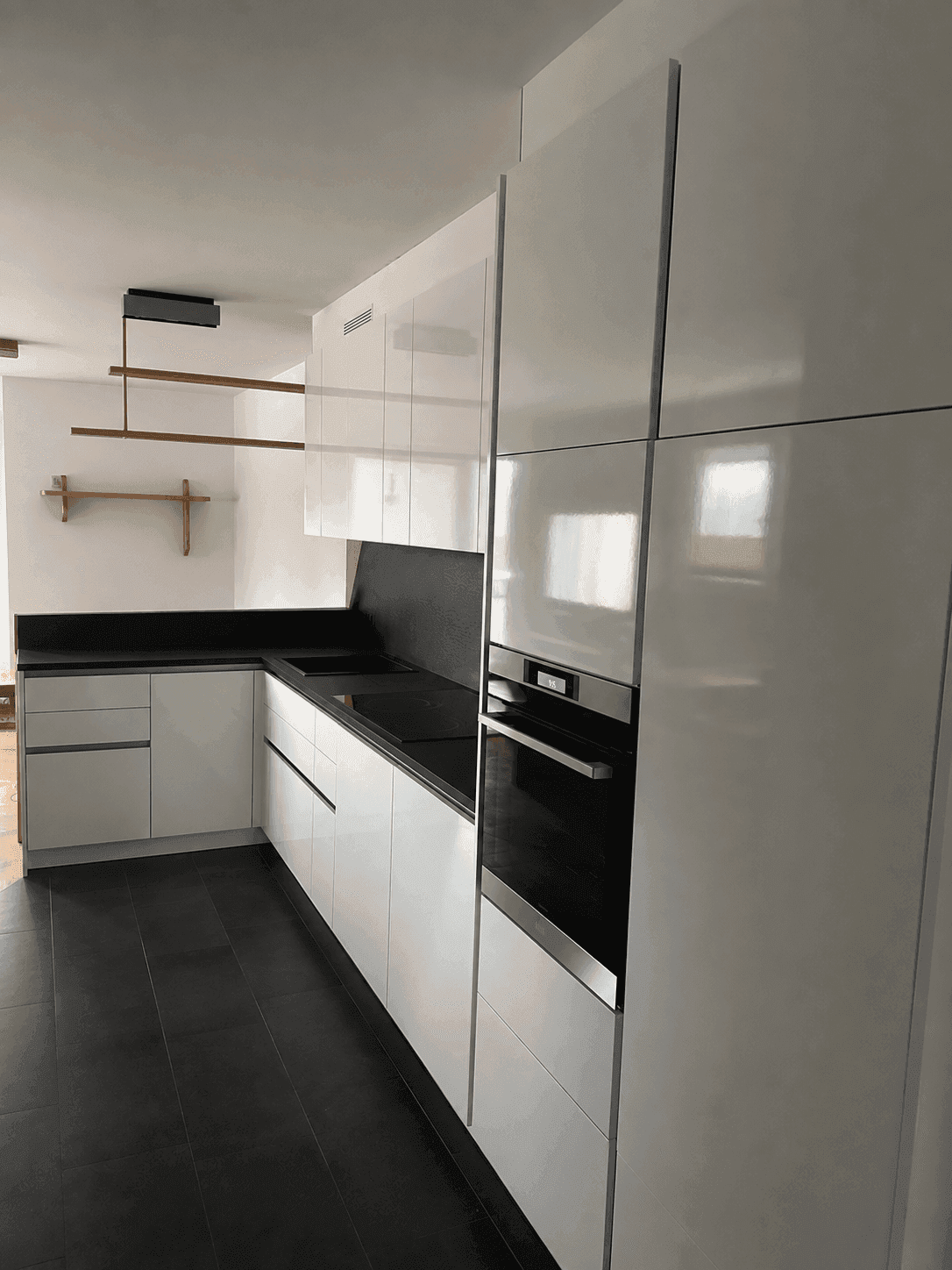 Moderne weiße Küche mit Hochglanzfronten und integriertem Backofen.