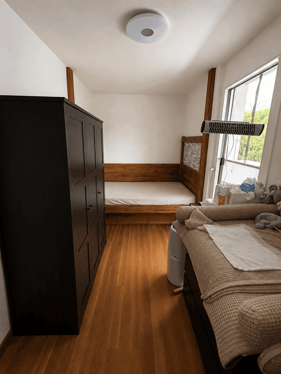 Gemütliches Zimmer mit Holzbett, dunklem Kleiderschrank und Parkettboden.