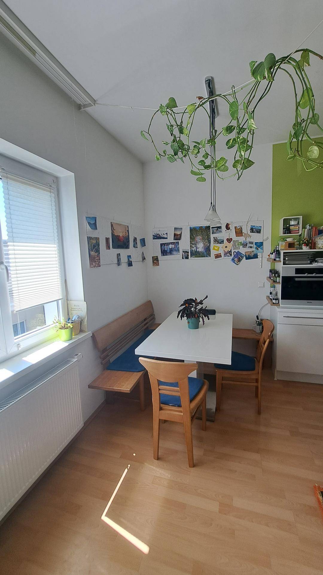 Heller Essbereich in der Küche mit Holztisch, Sitzbank und Fenster, dekoriert mit persönlichen Fotos.