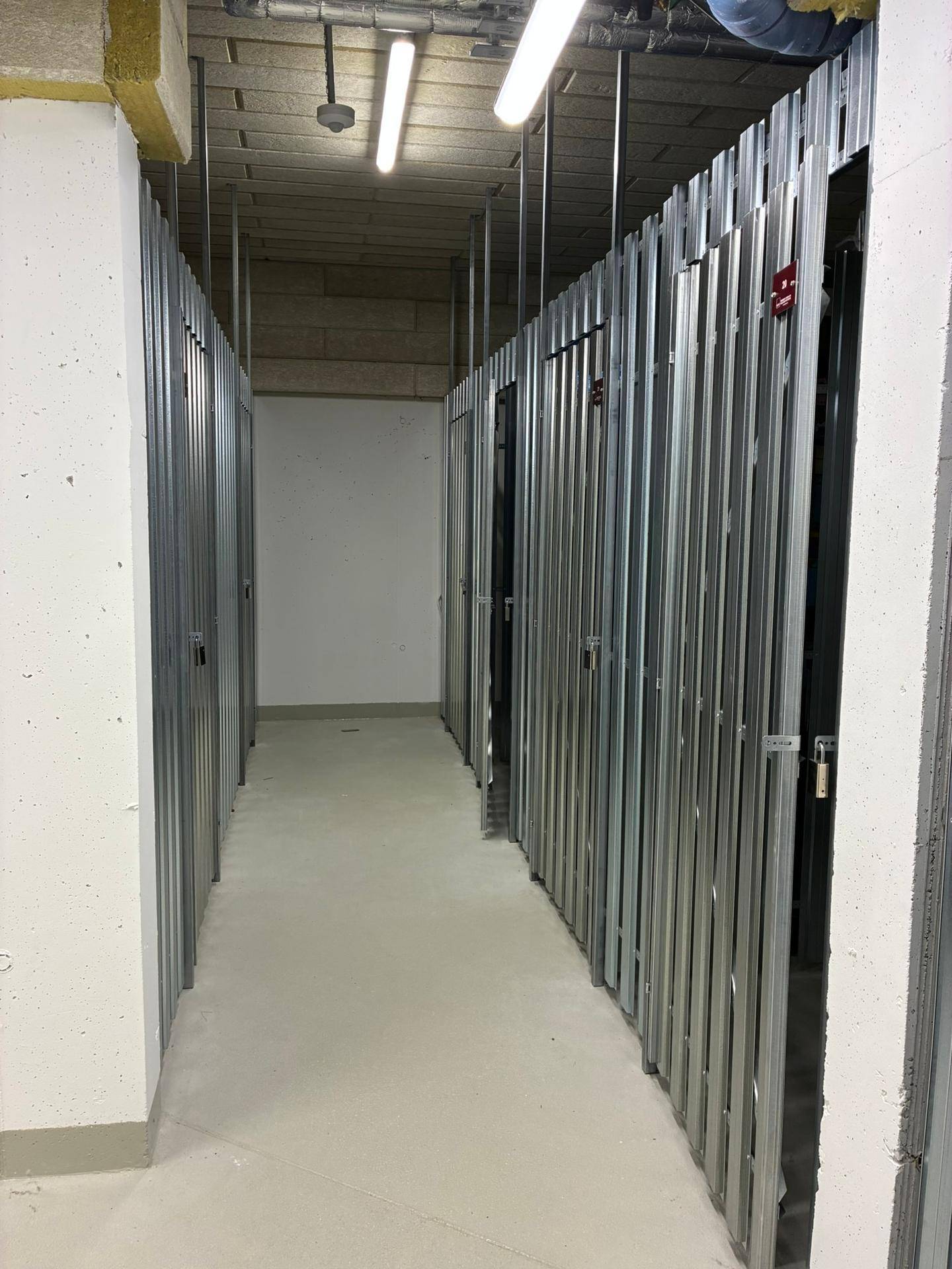Abstellräume im Kellerbereich mit Metallabtrennungen für zusätzlichen Stauraum.