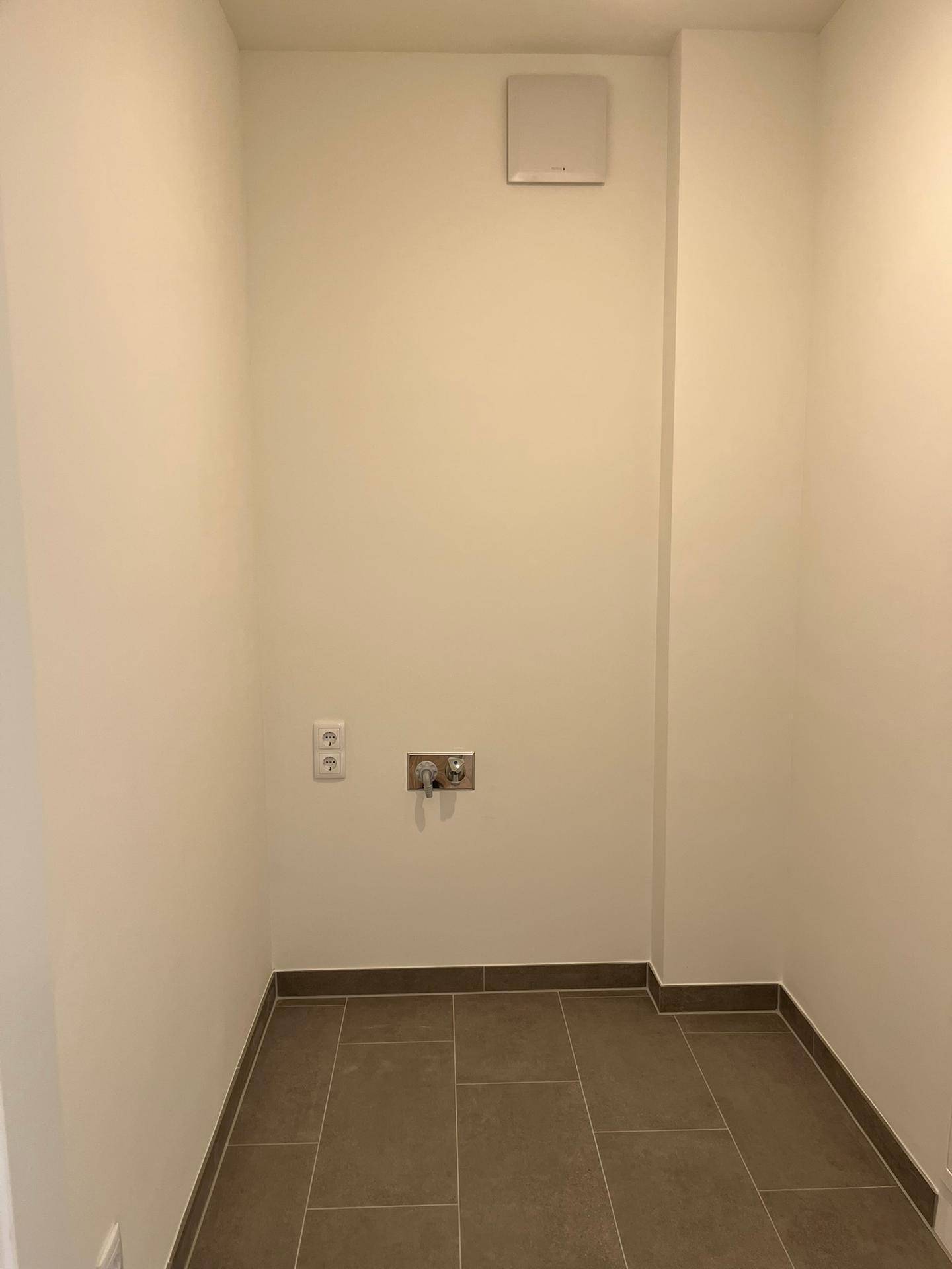 Praktischer Hauswirtschaftsraum mit Fliesenboden, Anschlüssen und Abluftventilator.