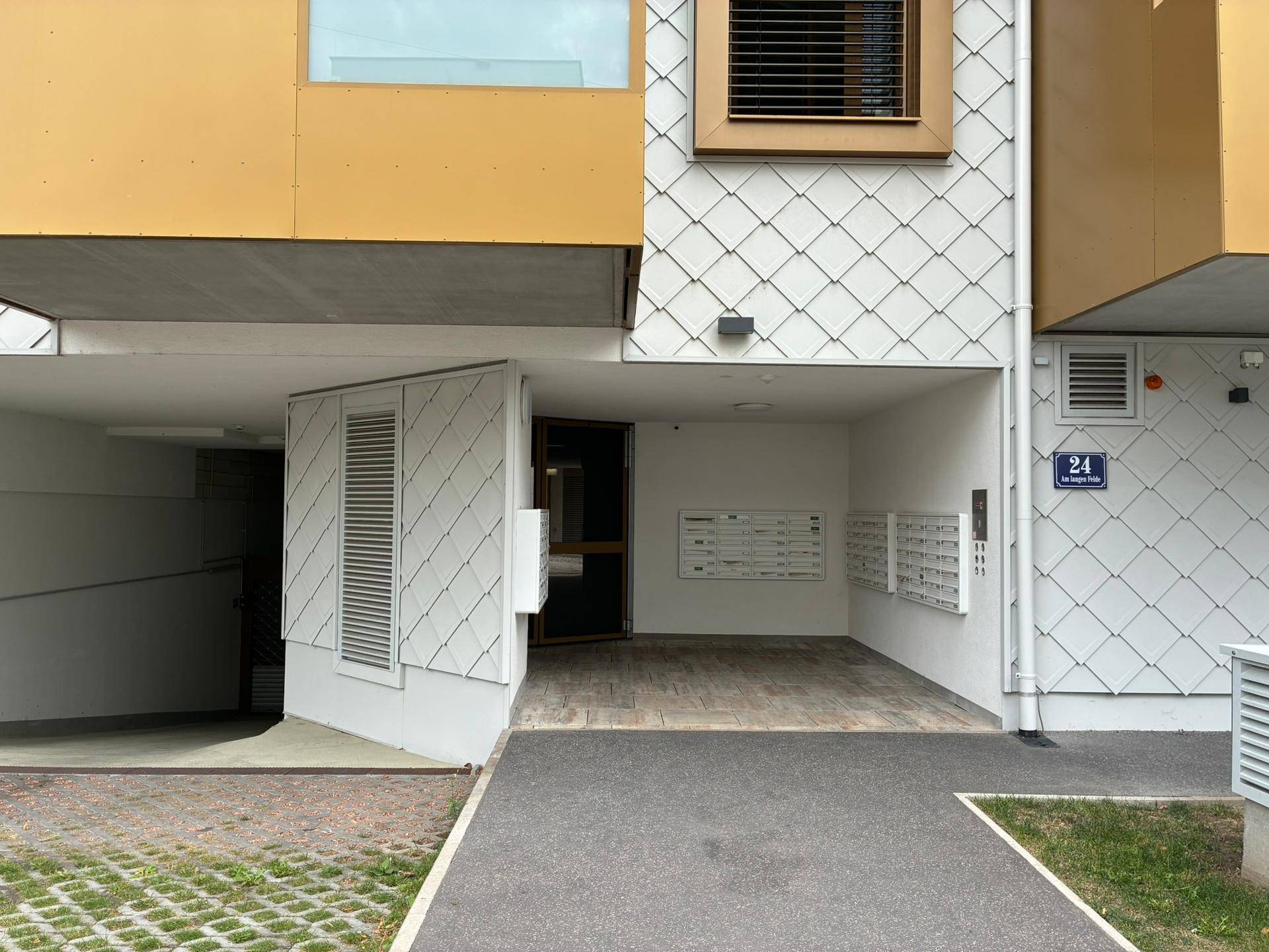 Moderner Eingangsbereich eines Wohnhauses mit Briefkästen und architektonischen Details.