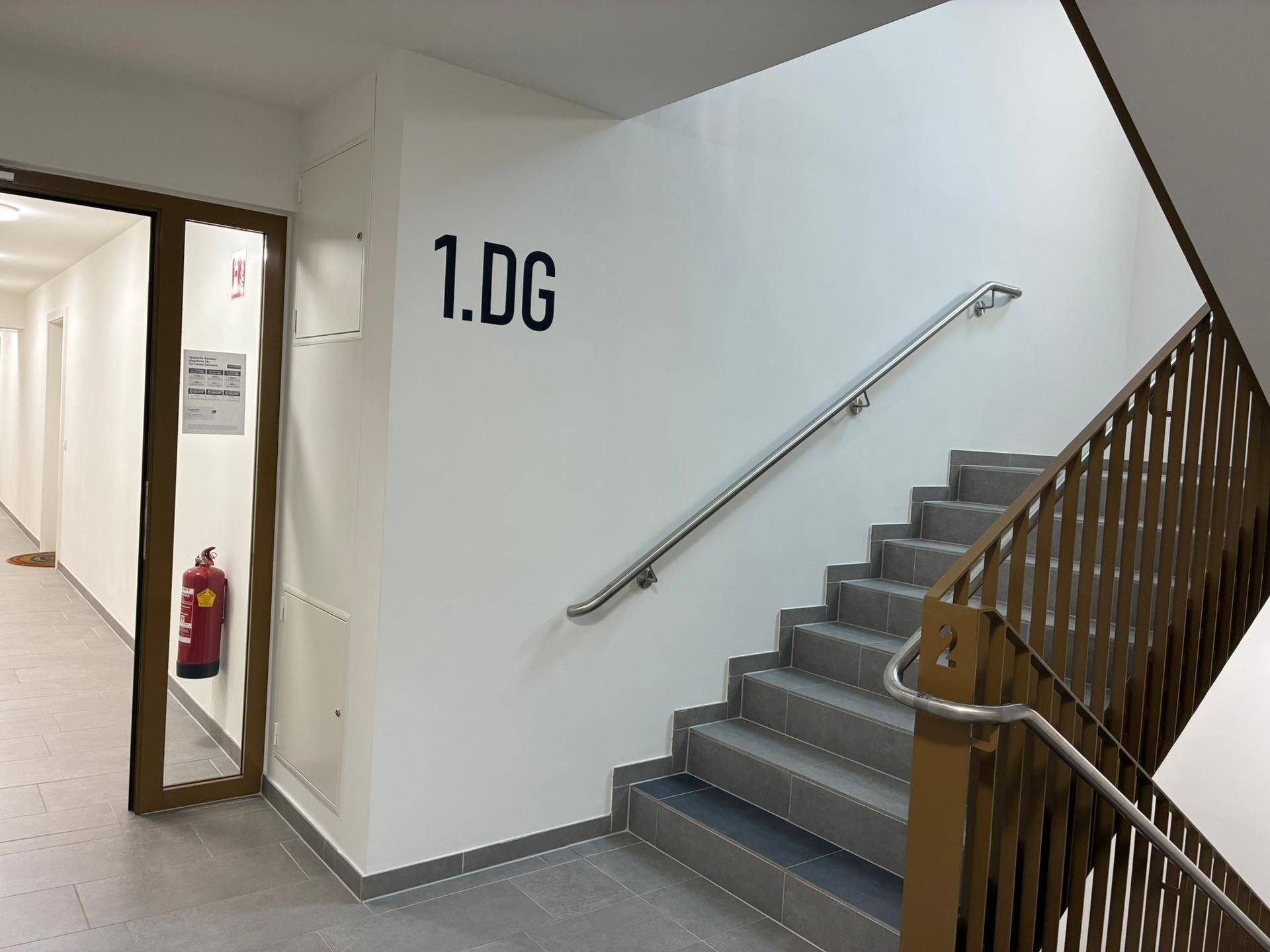 Modernes Treppenhaus mit Metallgeländer und Zugang zum ersten Dachgeschoss.