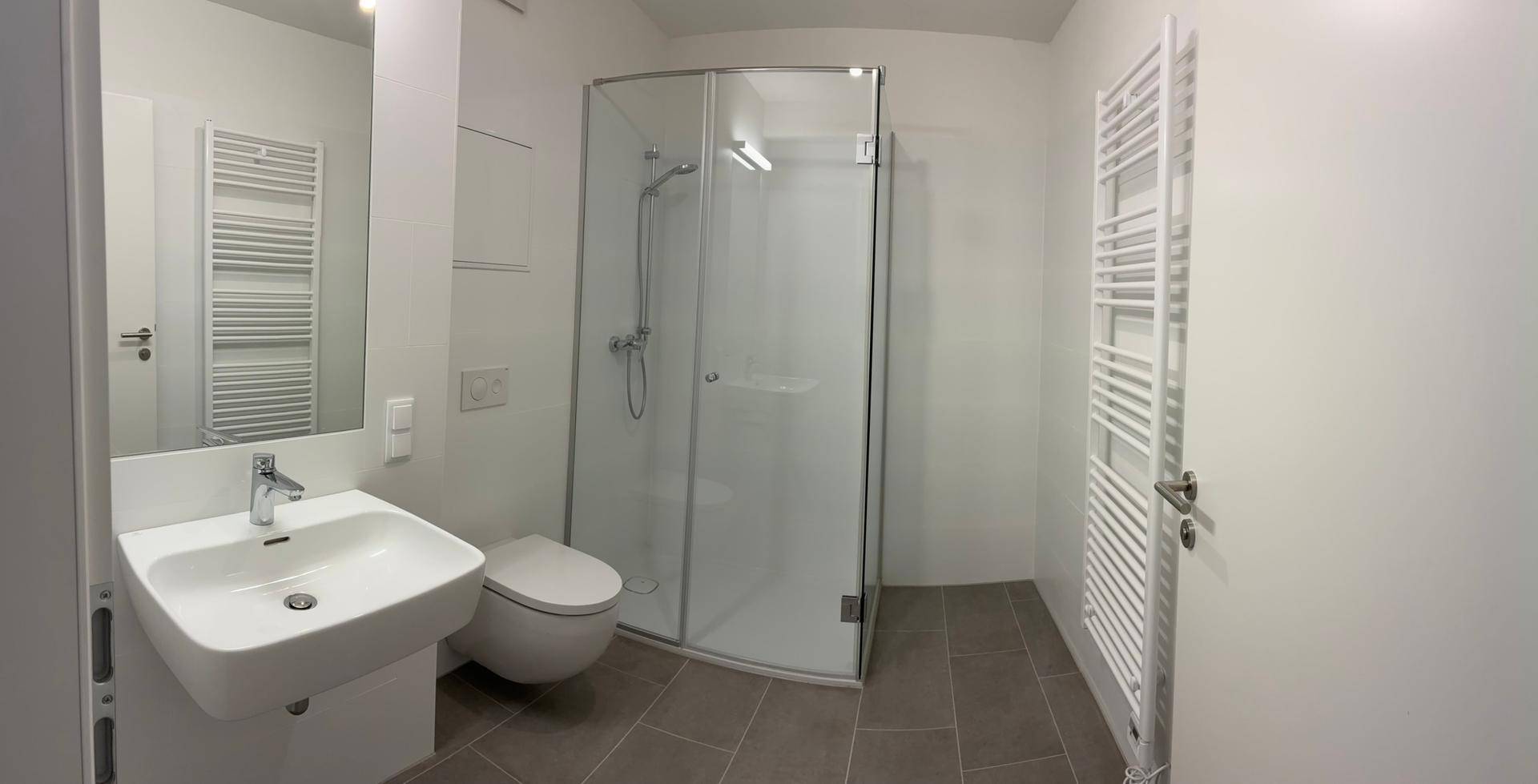 Modernes Badezimmer mit Duschkabine, Einzelwaschbecken und beheiztem Handtuchhalter.