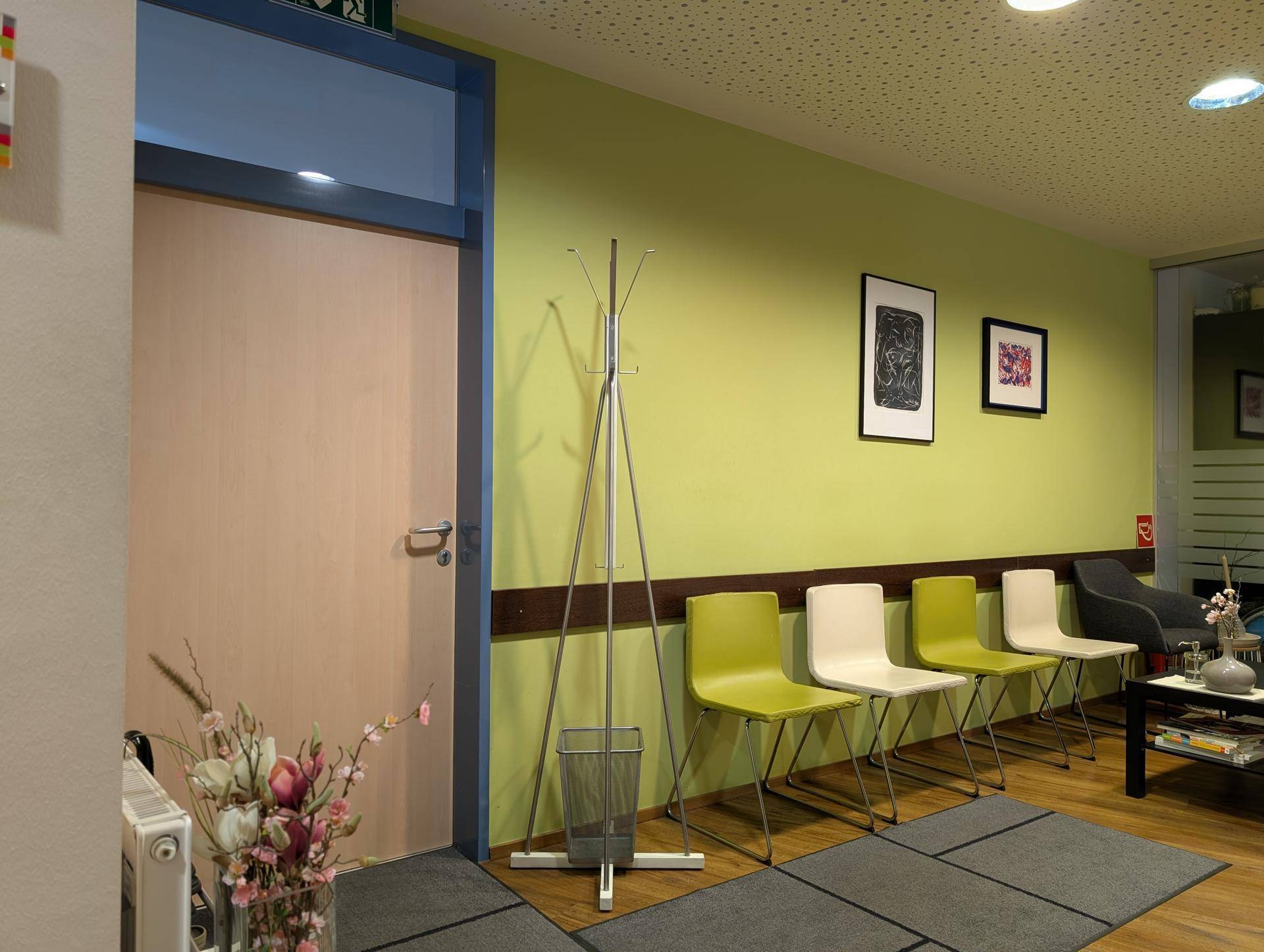 Eingangsbereich zum Wartezimmer mit Garderobe, bequemen Stühlen und einem hellen, freundlichen Ambiente.