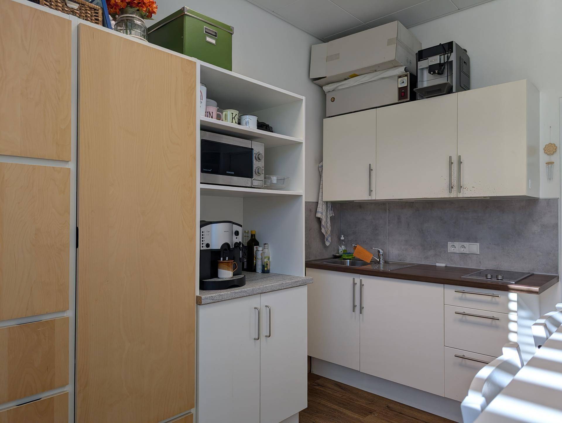 Funktionale Küchenzeile mit Mikrowelle, Kaffeemaschine und ausreichend Stauraum in den Schränken.