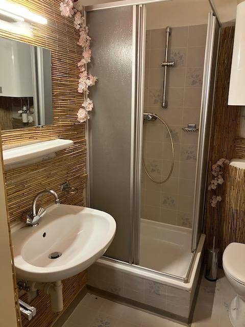 Badezimmer mit Duschkabine, Waschbecken und Bambus-Wandverkleidung.