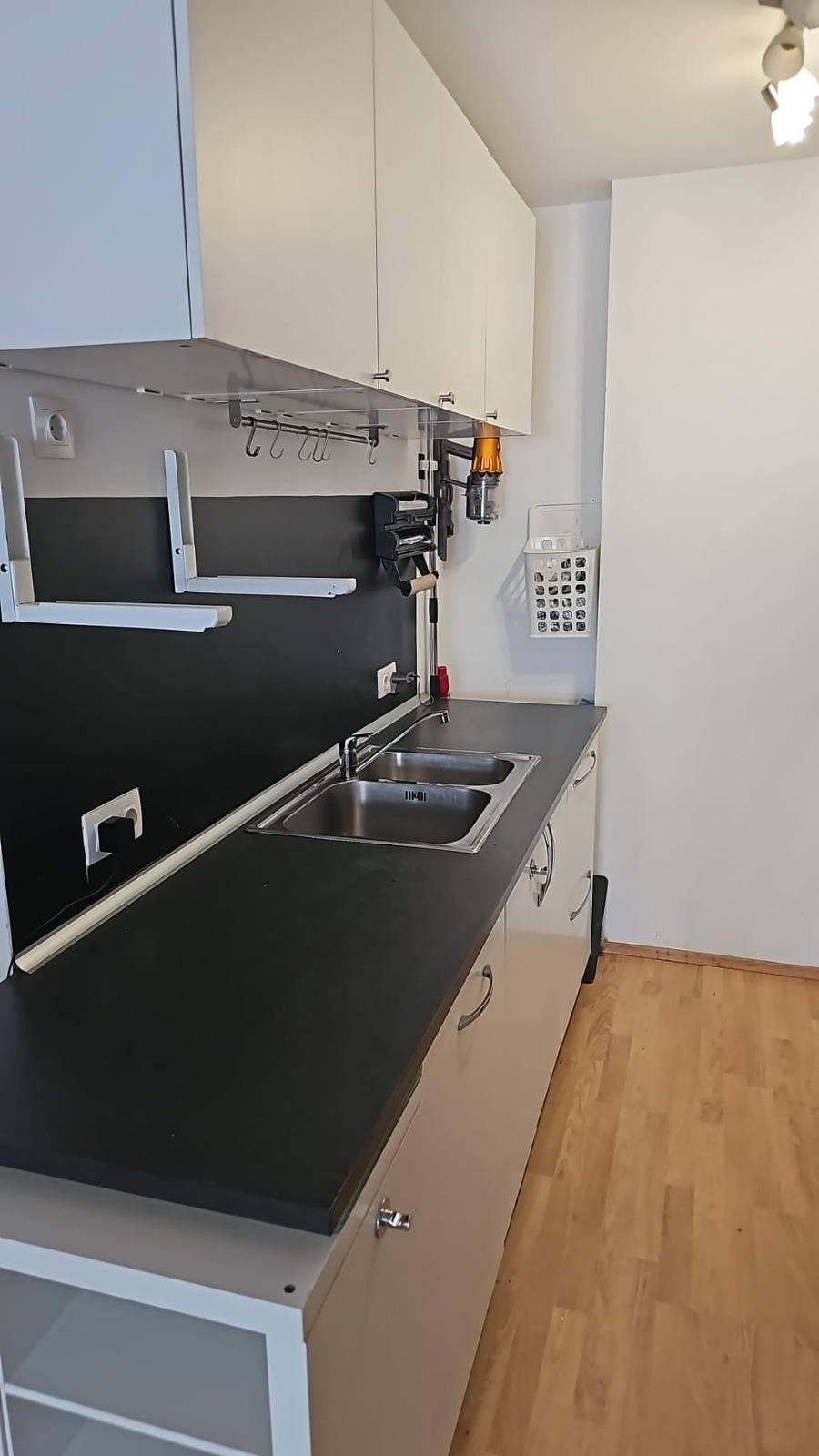 Küchenzeile mit Doppelspüle, dunkler Arbeitsplatte und weißen Oberschränken.