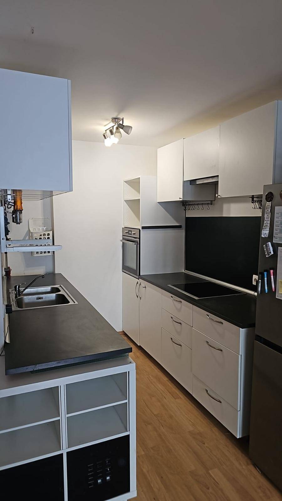 Moderne Küche mit weißen Schränken, dunklen Arbeitsplatten und integrierten Geräten.