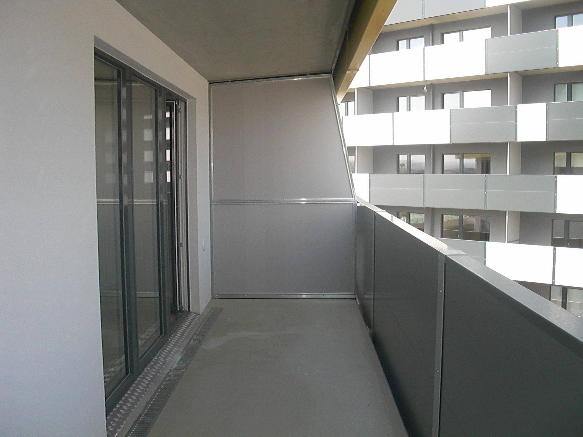 Heller Balkon mit Schiebetüren und Blick auf die gegenüberliegende Wohnanlage.