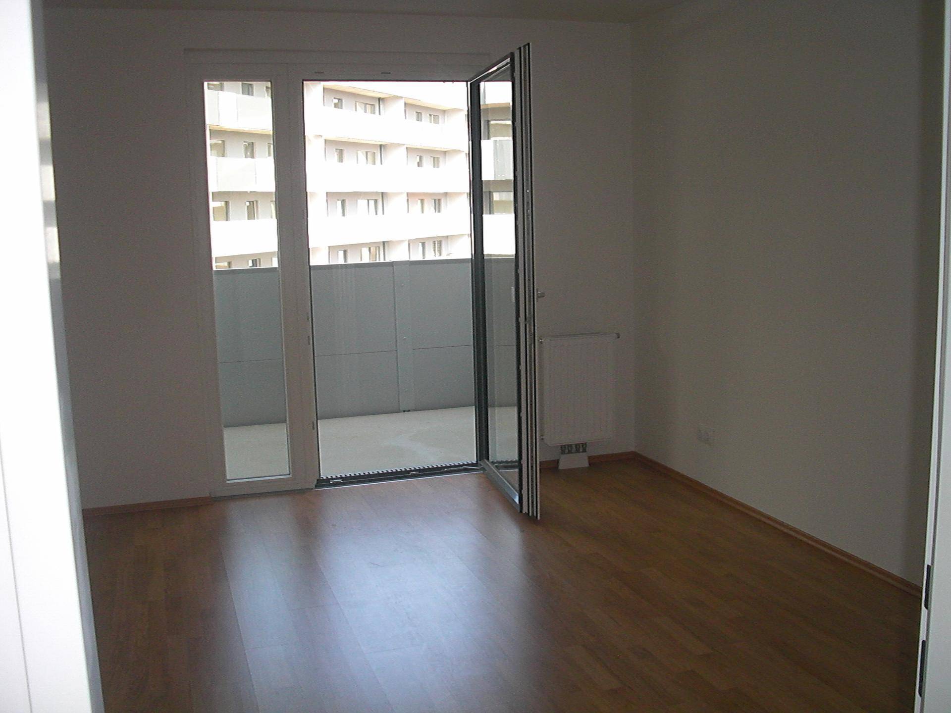 Geräumiges Zimmer mit großen Fenstern und direktem Zugang zum Balkon.
