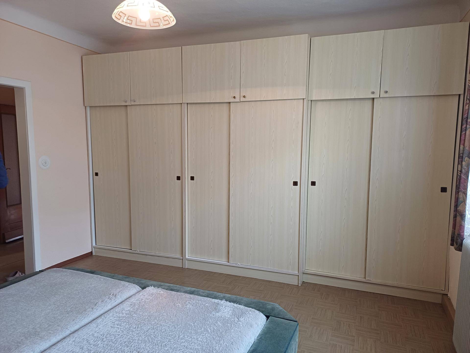 Schlafzimmer mit großem Einbauschrank und zwei Einzelbetten.