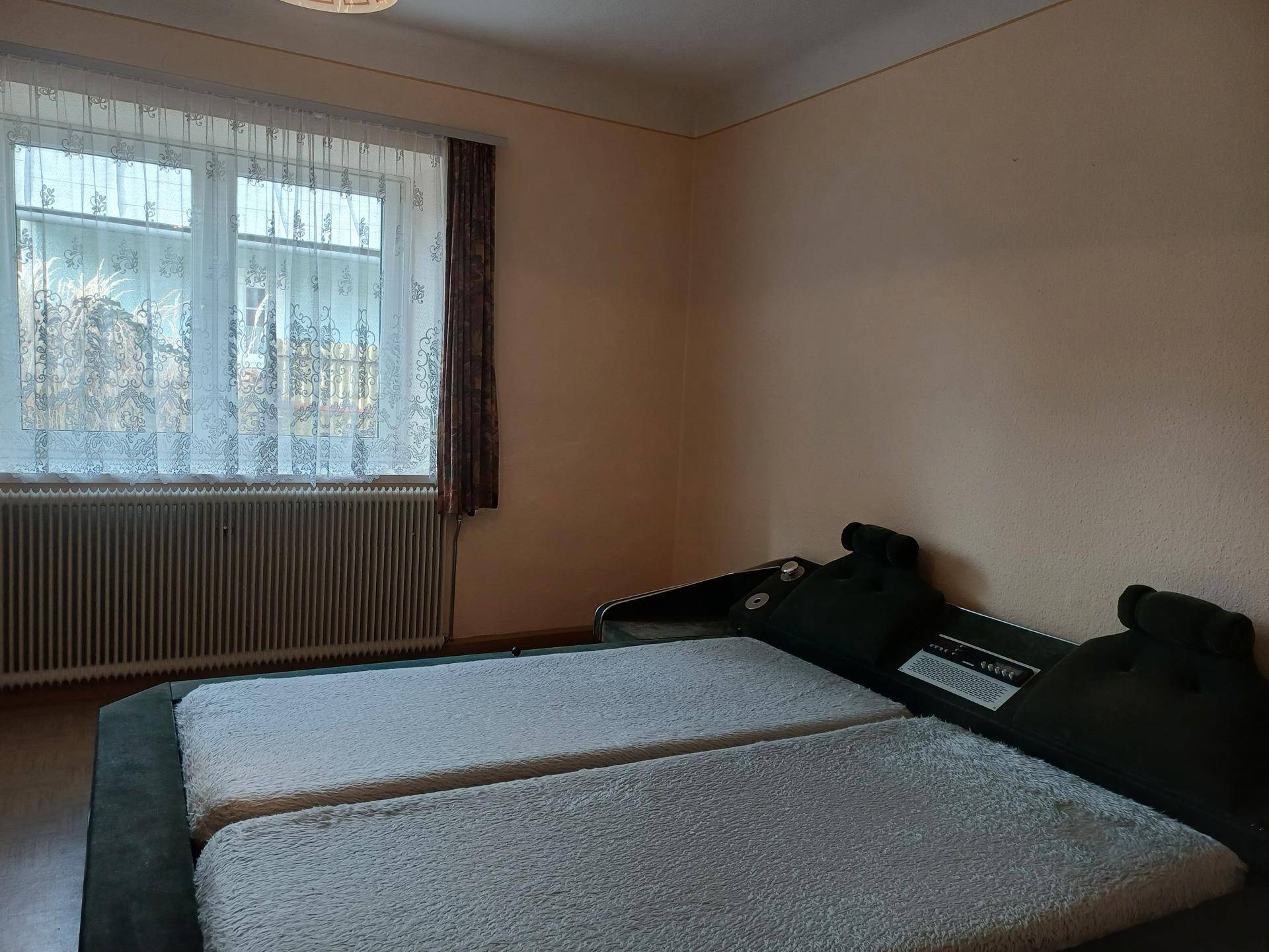 Schlafzimmer mit zwei Einzelbetten, Fenster und hellem Teppichboden.