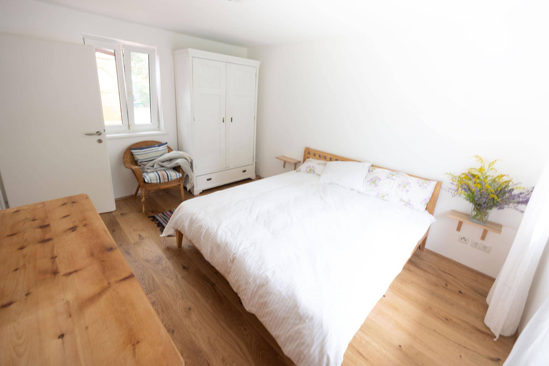 Gemütliches Schlafzimmer mit Holzbett, weißem Kleiderschrank und hellem Holzfußboden.