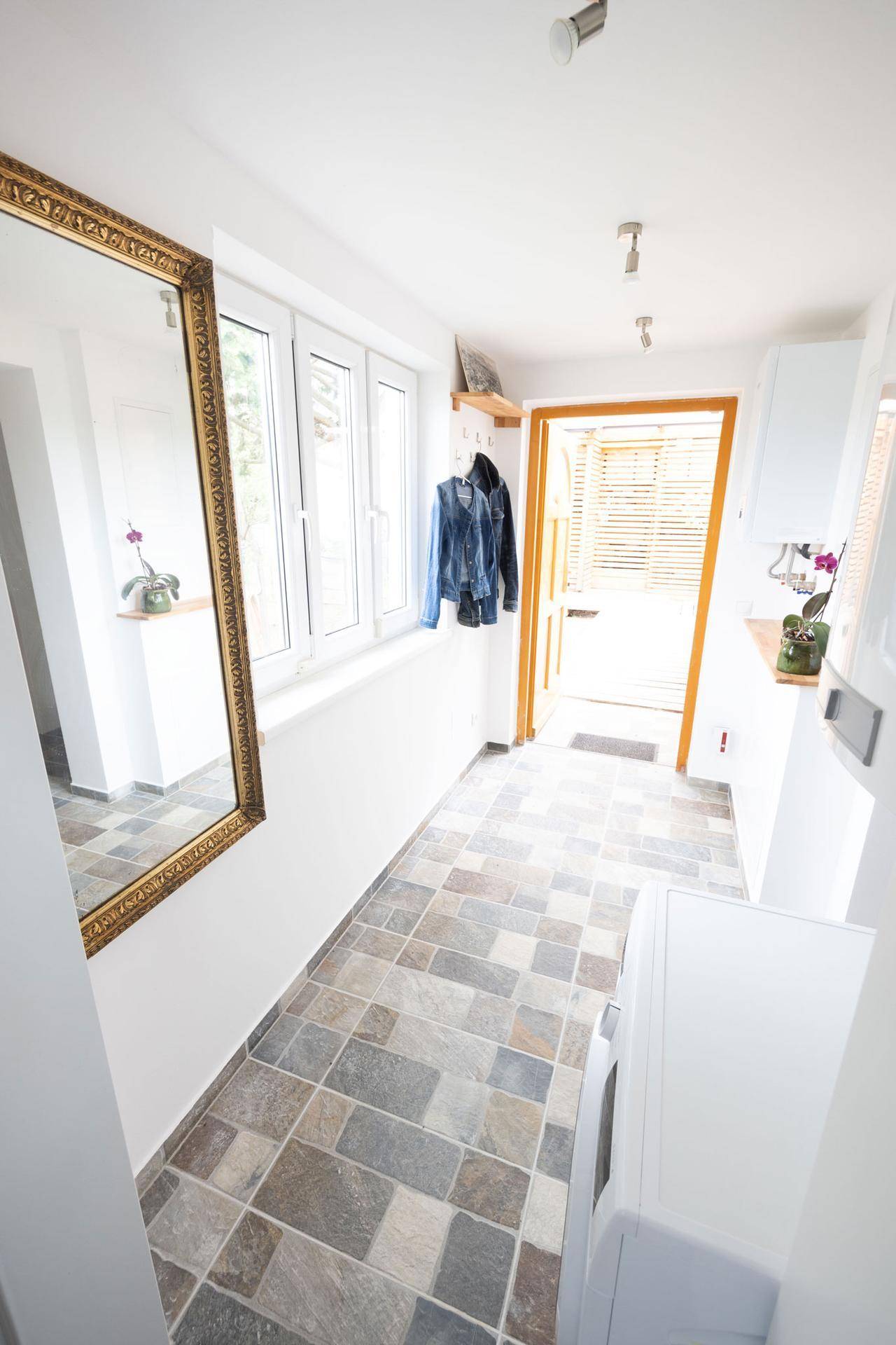 Heller Eingangsbereich mit großem Spiegel, Fenster und praktischer Garderobe.