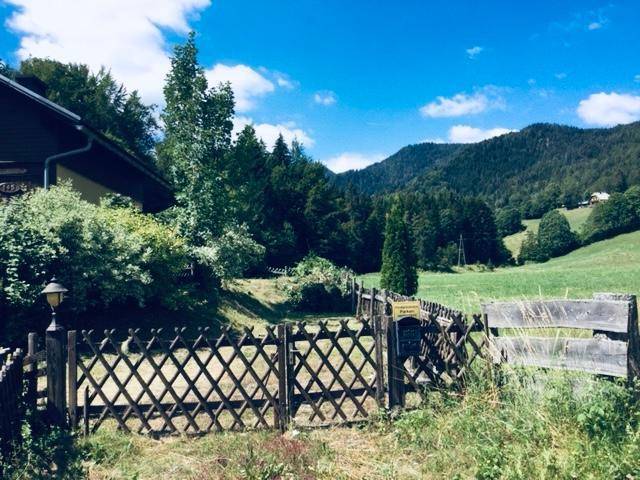 Seitlicher Blick auf das Haus und den Zaun, der zu einer weiten Wiesenlandschaft führt.
