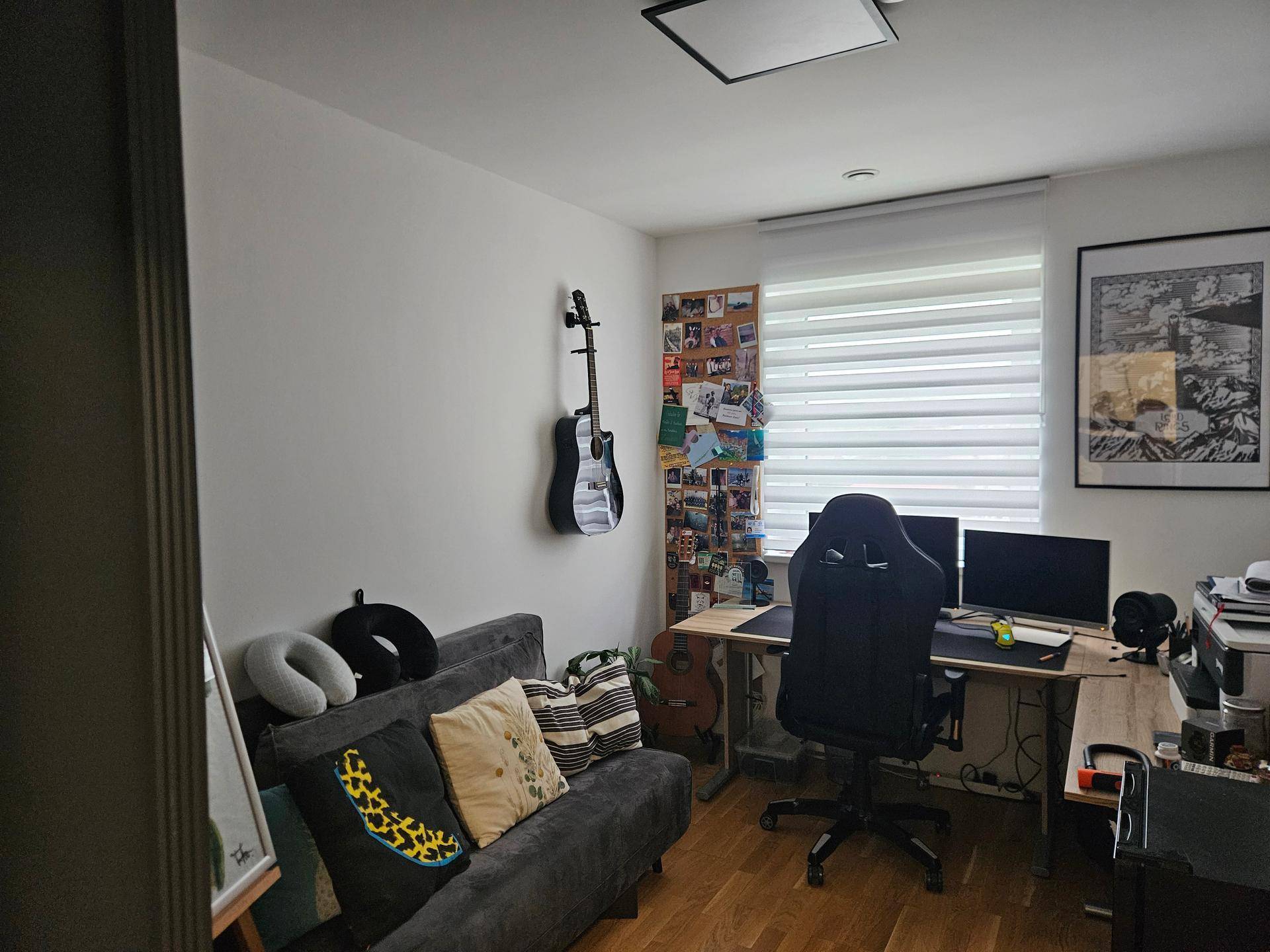 Arbeitszimmer mit Schreibtisch, Sofa und Gitarre an der Wand.