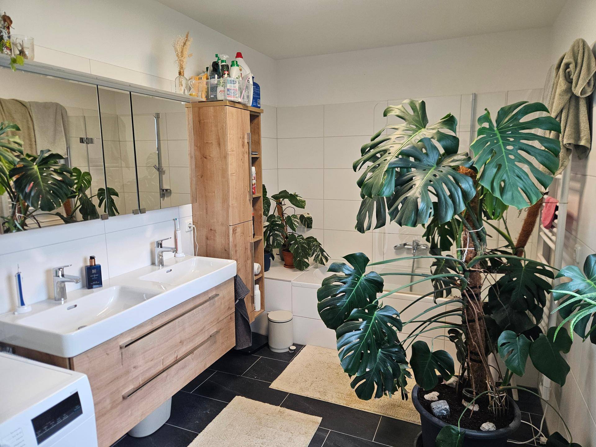 Geräumiges Badezimmer mit Doppelwaschbecken, Badewanne und großen Pflanzen.
