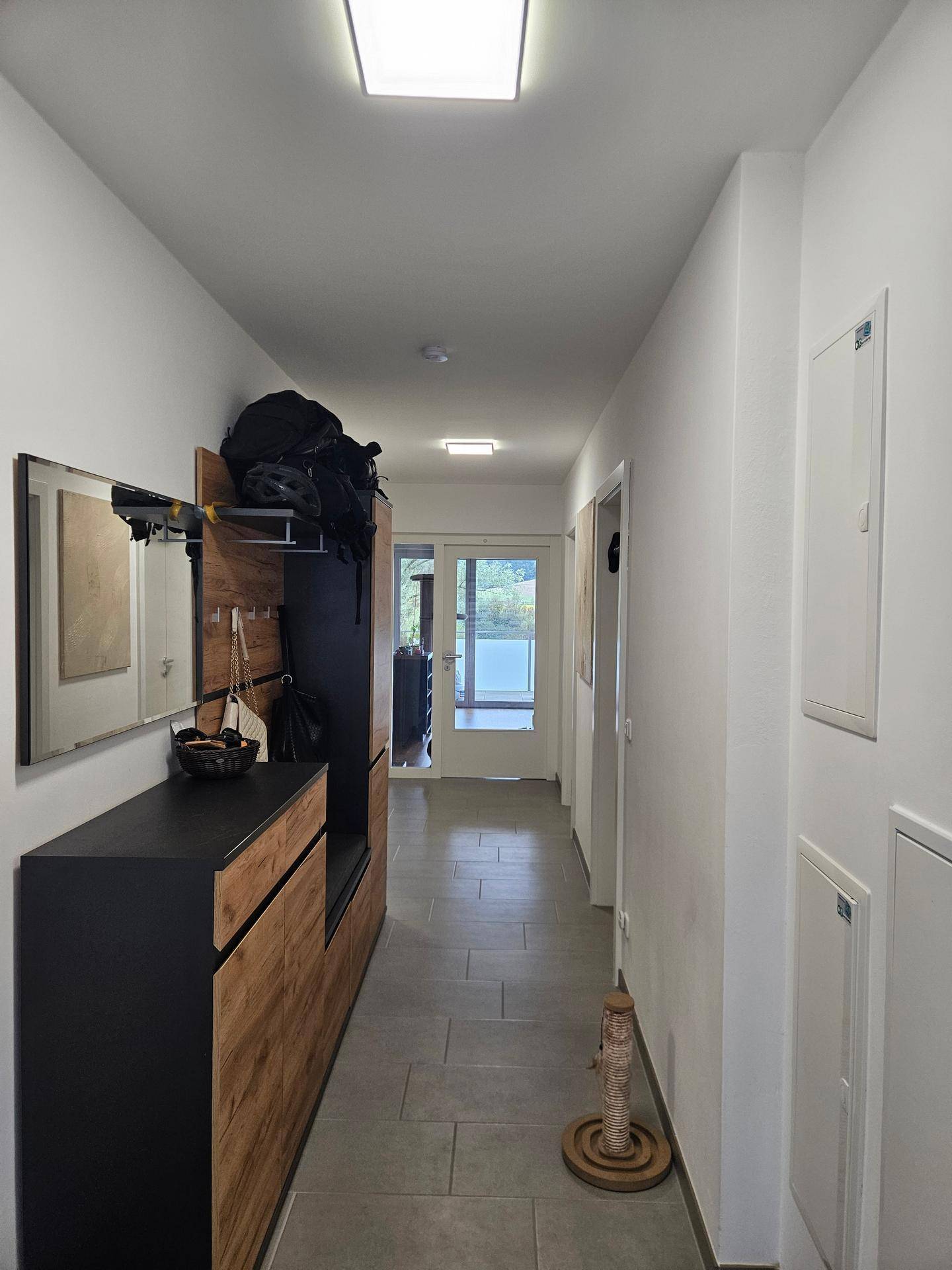 Langer Flur mit modernen Fliesen, Garderobe und Spiegel.