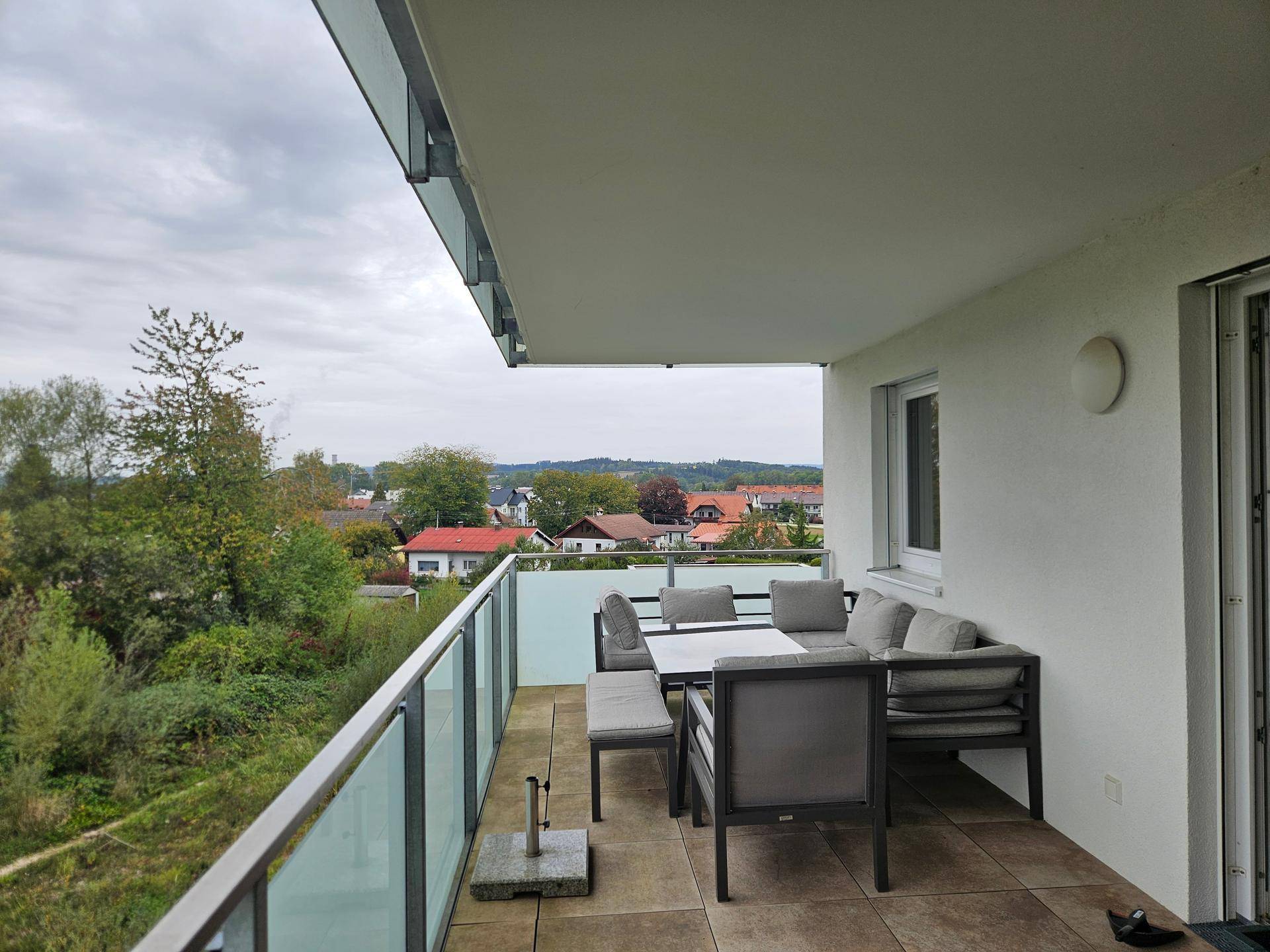 Großer Balkon mit Outdoor-Sitzgruppe und Blick auf die Umgebung.