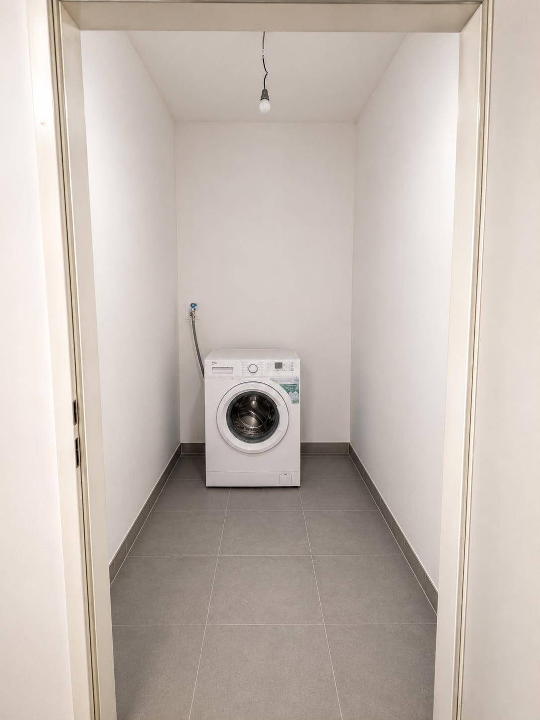 Praktischer Hauswirtschaftsraum mit Waschmaschine und gefliestem Boden für den täglichen Gebrauch.