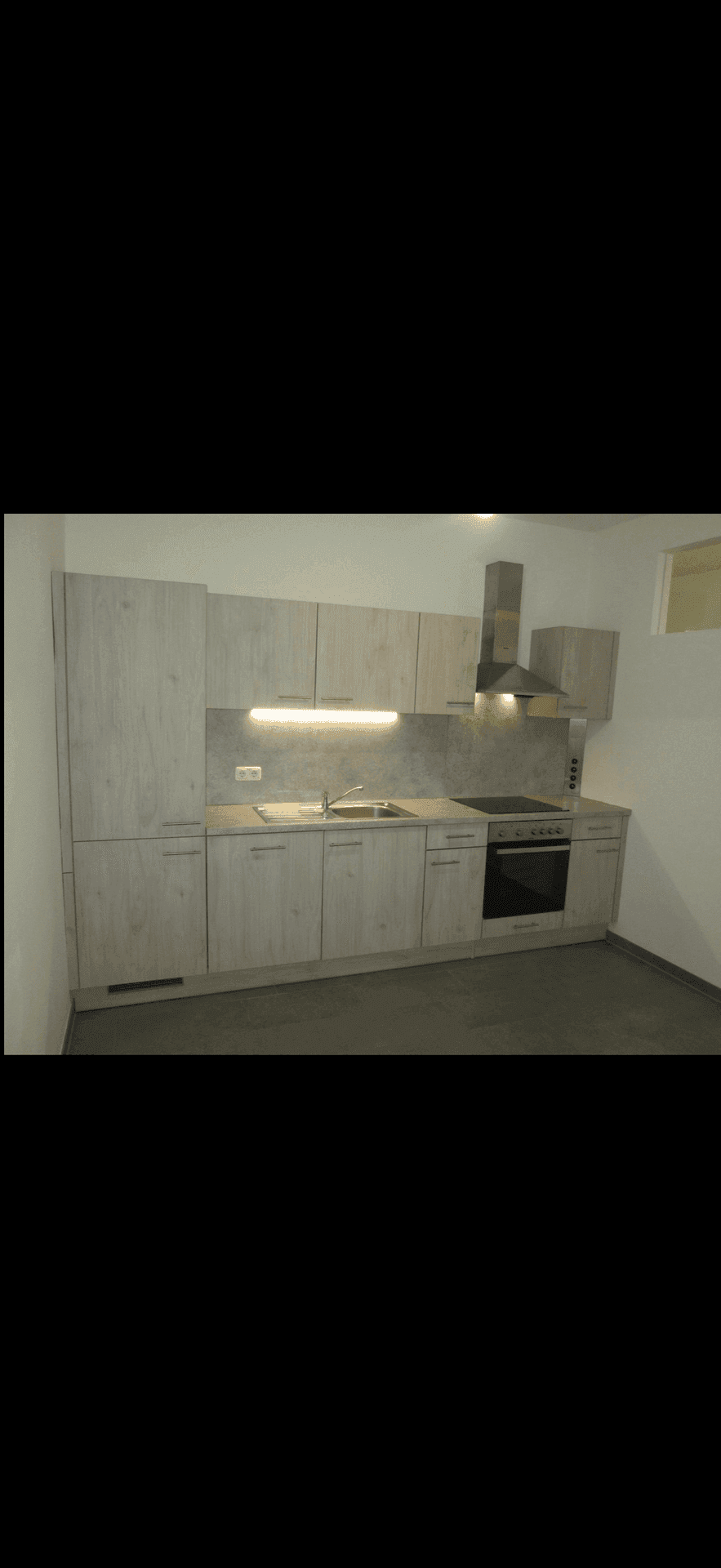 Moderne Einbauküche mit hellen Holzfronten, integrierten Geräten und Dunstabzugshaube.