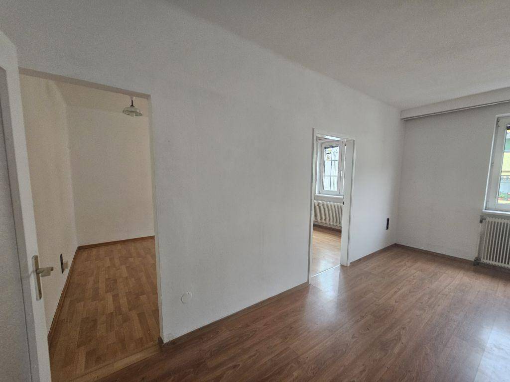 Geräumiger Wohnbereich mit hellem Laminatboden und Zugang zu angrenzenden Zimmern.