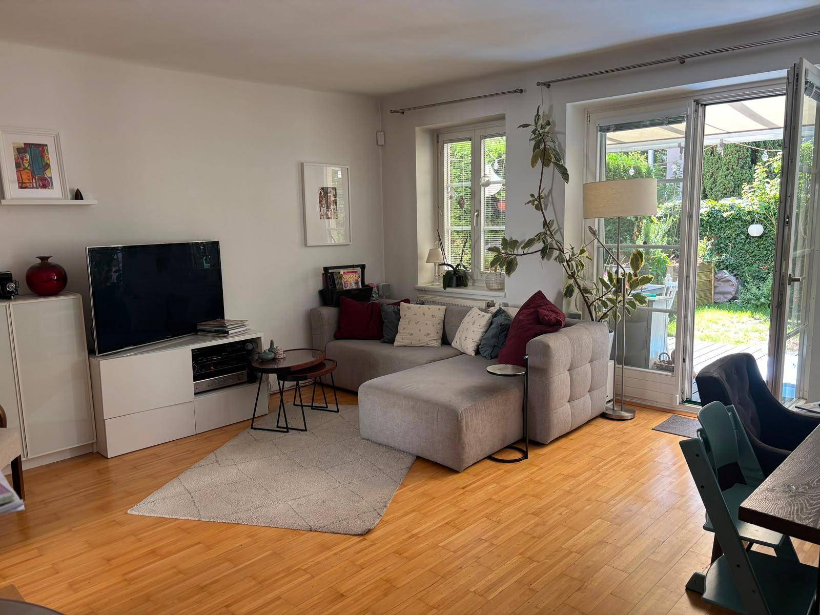 Helles Wohnzimmer mit großem Sofa, TV-Möbeln und direktem Zugang zur Terrasse und zum Garten.