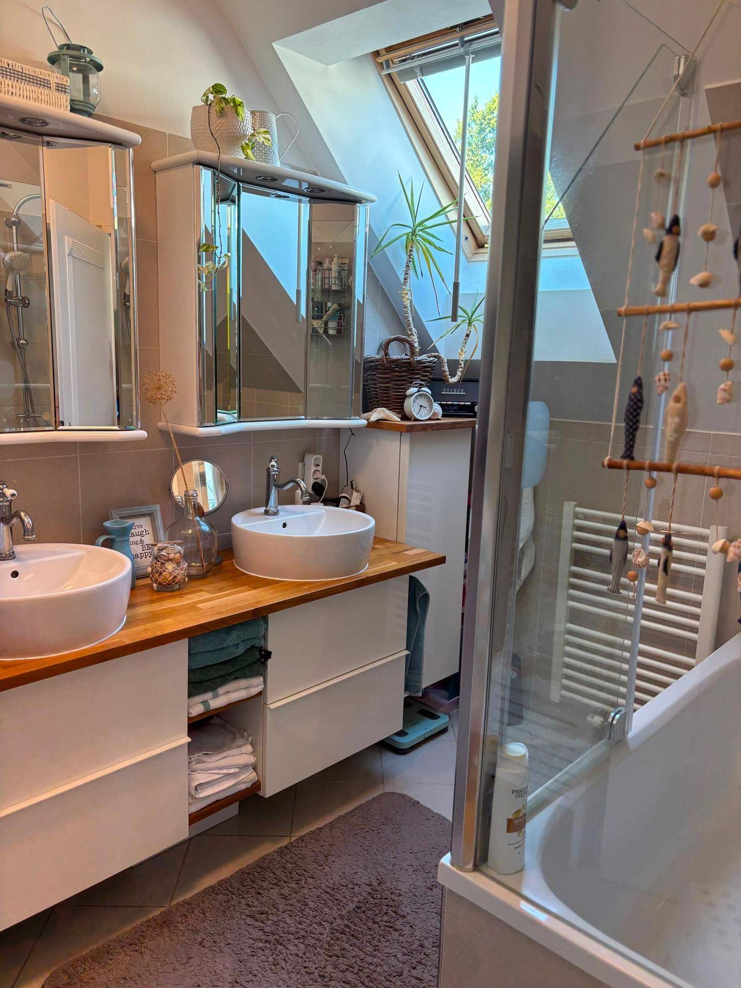Modernes Badezimmer mit Doppelwaschbecken, Dusche, Badewanne und einem Dachfenster.