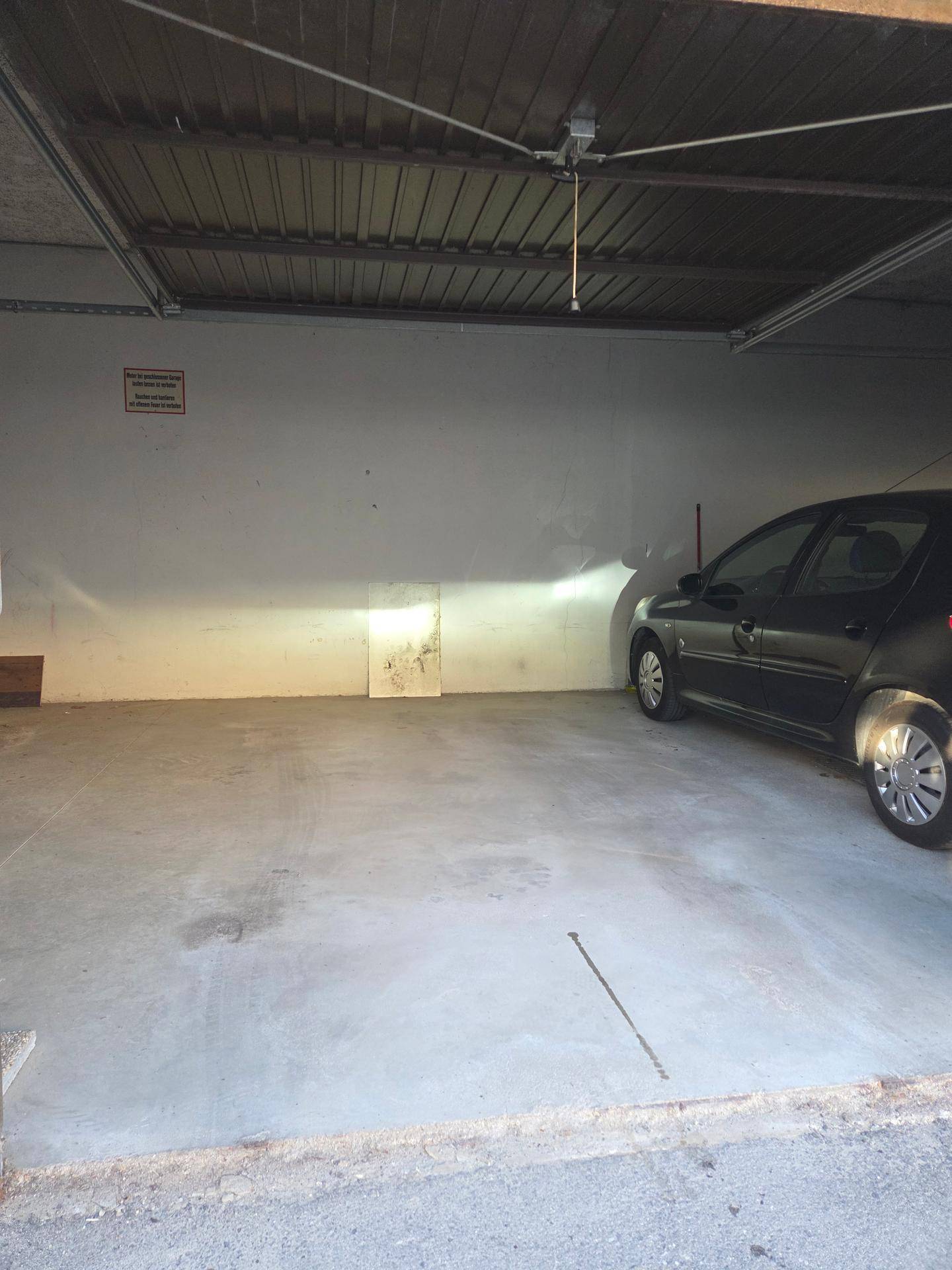 Geräumige Garage mit Betonboden und einem geparkten Auto, bietet sicheren Stellplatz.