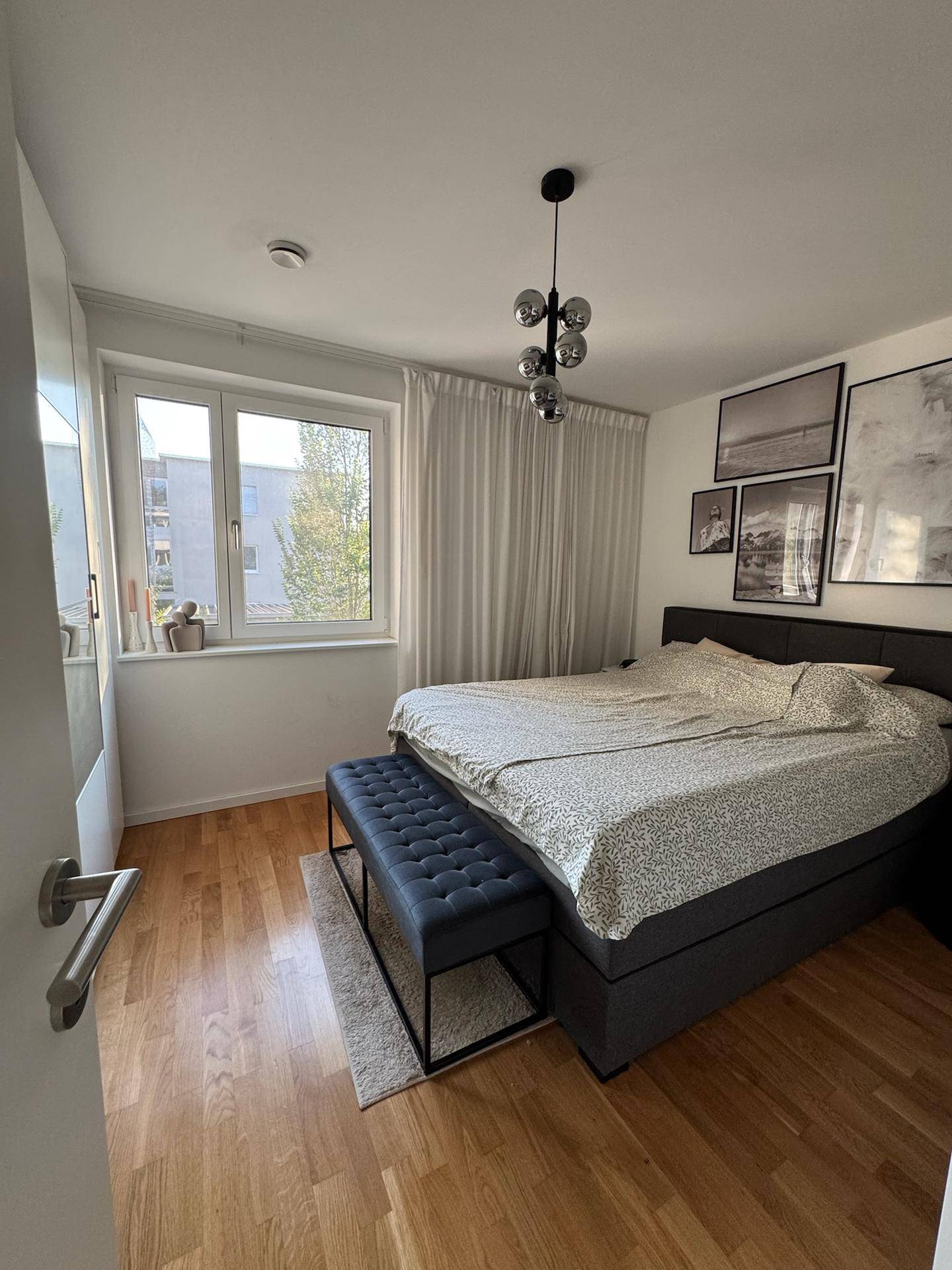 Helles Schlafzimmer mit Doppelbett, Sitzbank und einem angenehmen Blick ins Grüne.