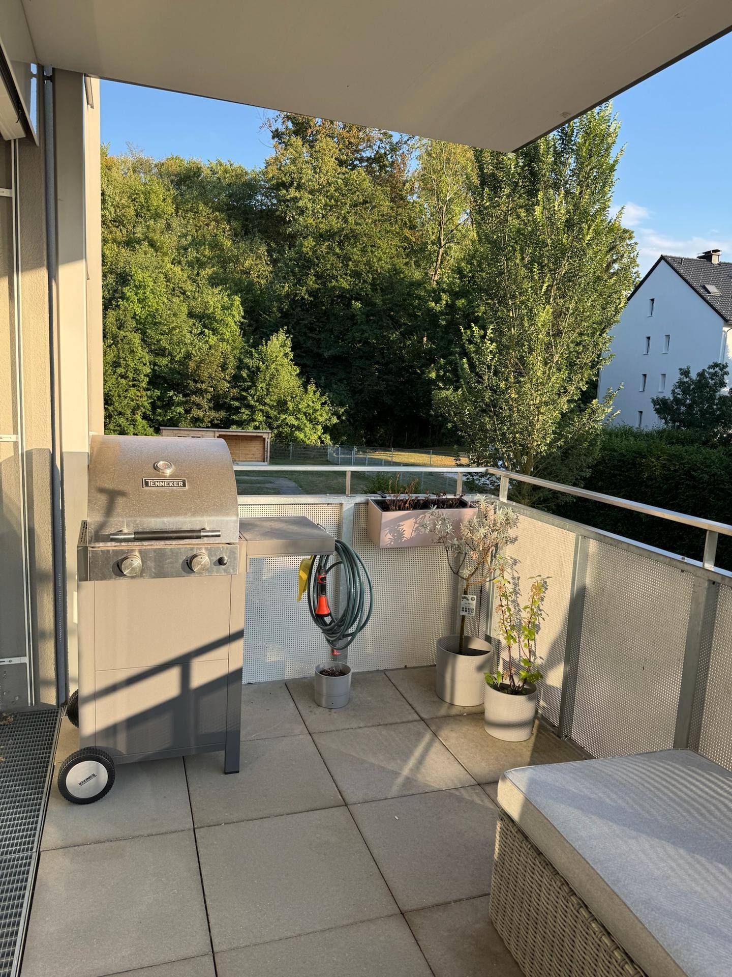 Sonniger Balkon mit Gasgrill, Pflanzen und einem schönen Blick ins Grüne.