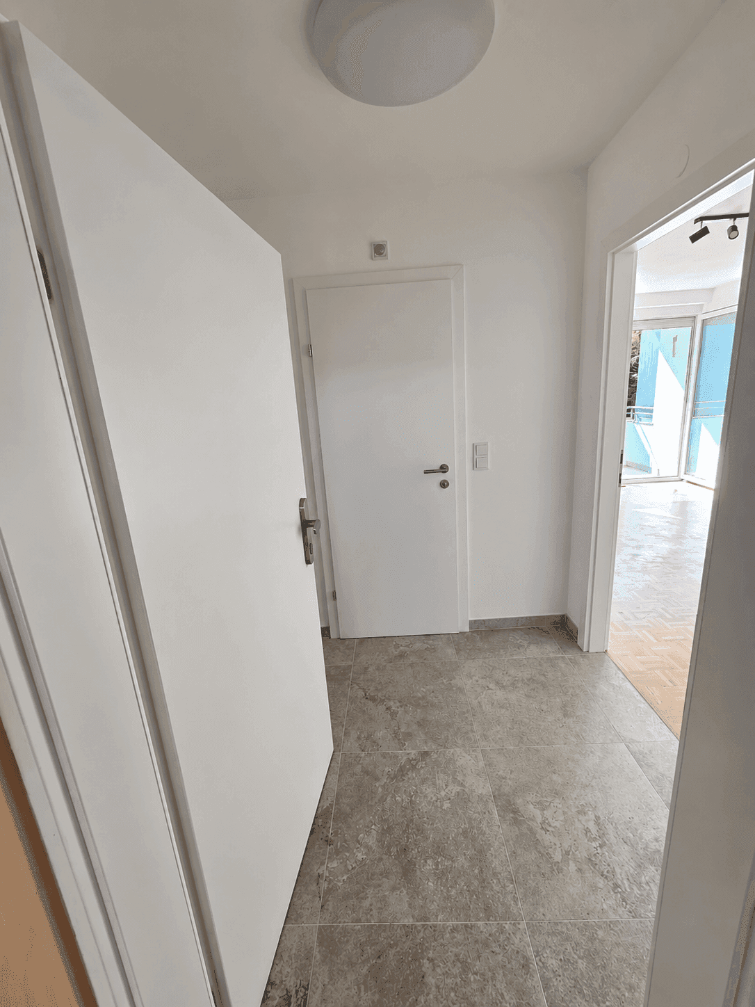 Heller Flur mit modernen Fliesen und weißen Türen, der zu den verschiedenen Räumen der Wohnung führt.