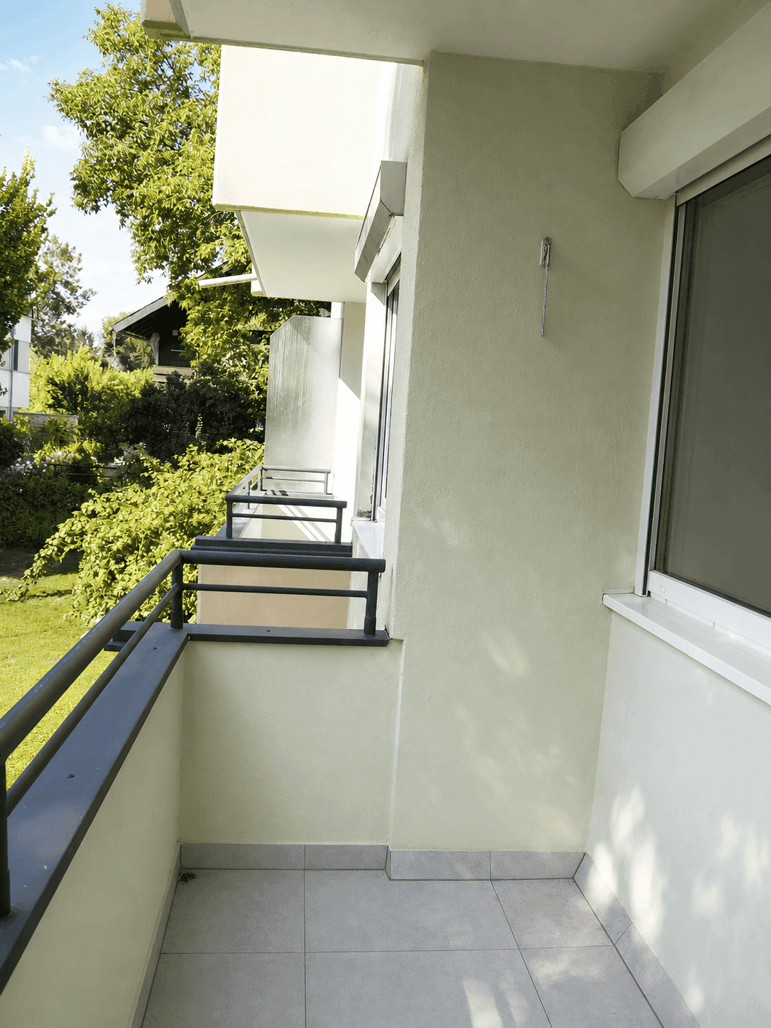 Kleiner Balkon mit Fliesenboden und Blick ins Grüne, perfekt für entspannte Momente im Freien.