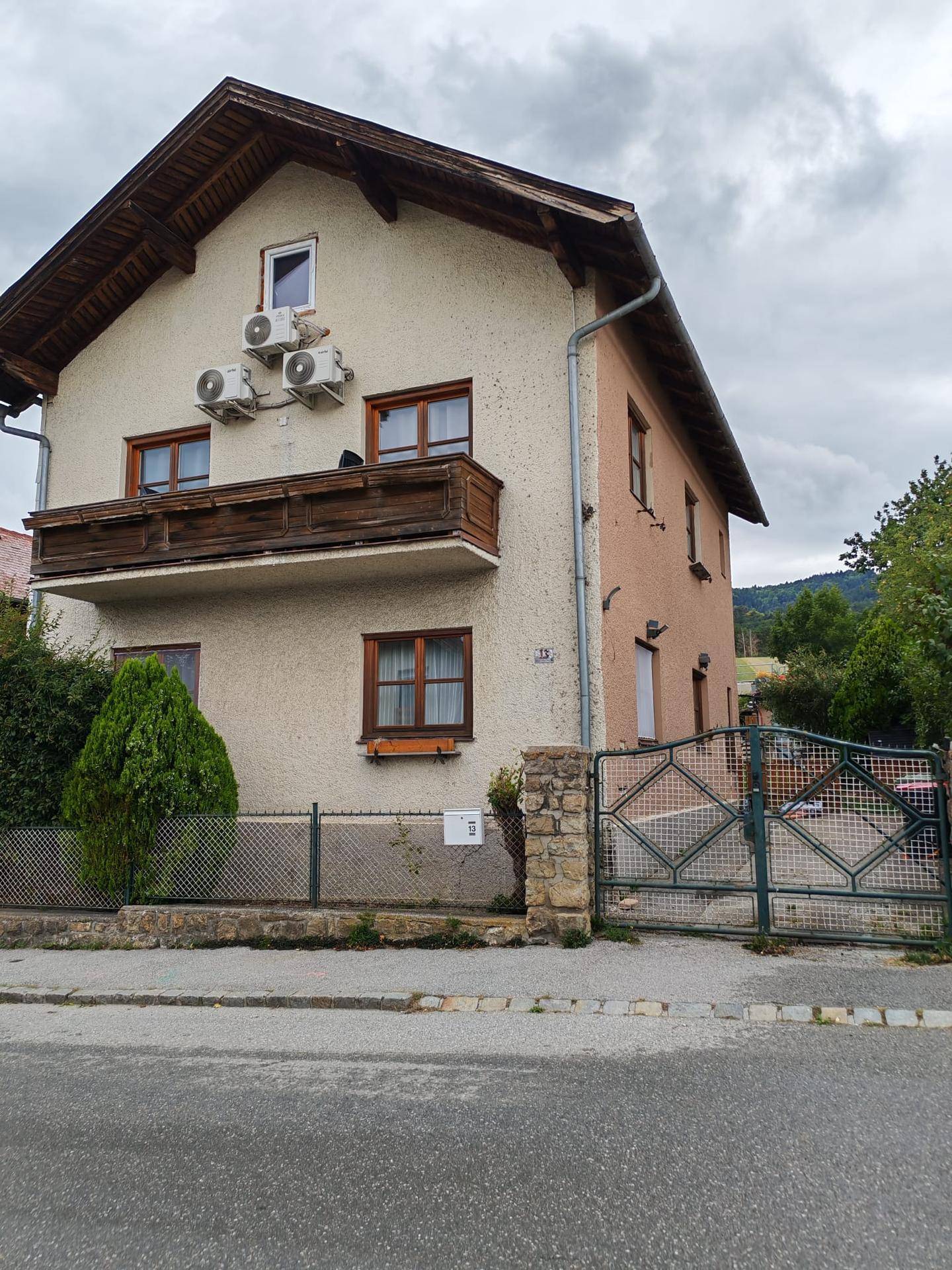 Fassade eines Hauses mit Balkon, Klimaanlagen-Außengeräten und einem Gartentor.
