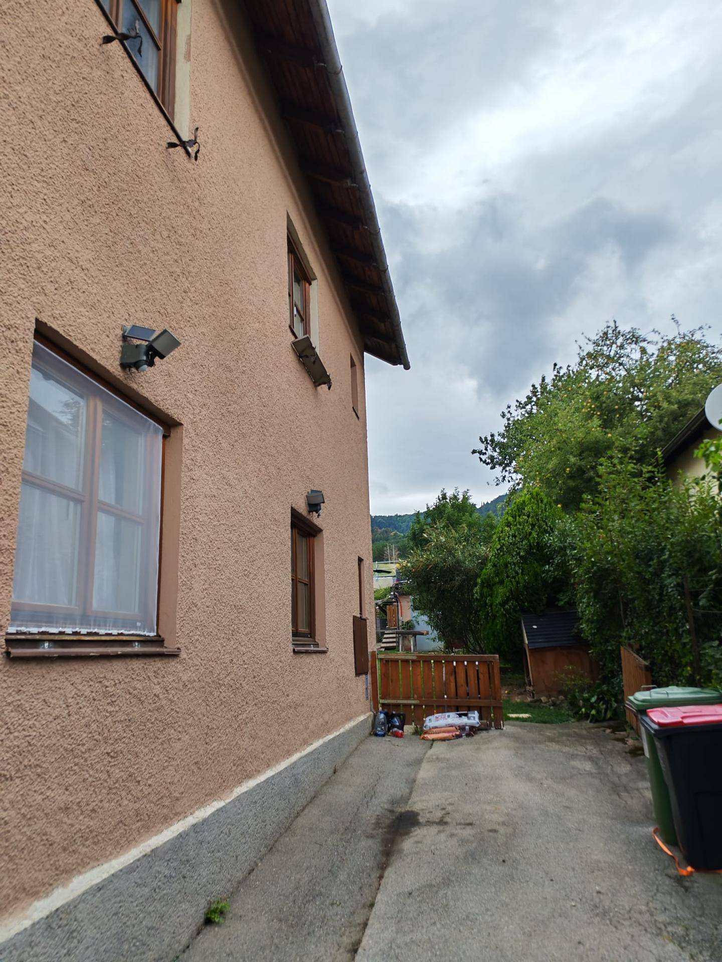 Seitenansicht eines Hauses mit Fenstern, Außenbeleuchtung und Zugang zum Gartenbereich.