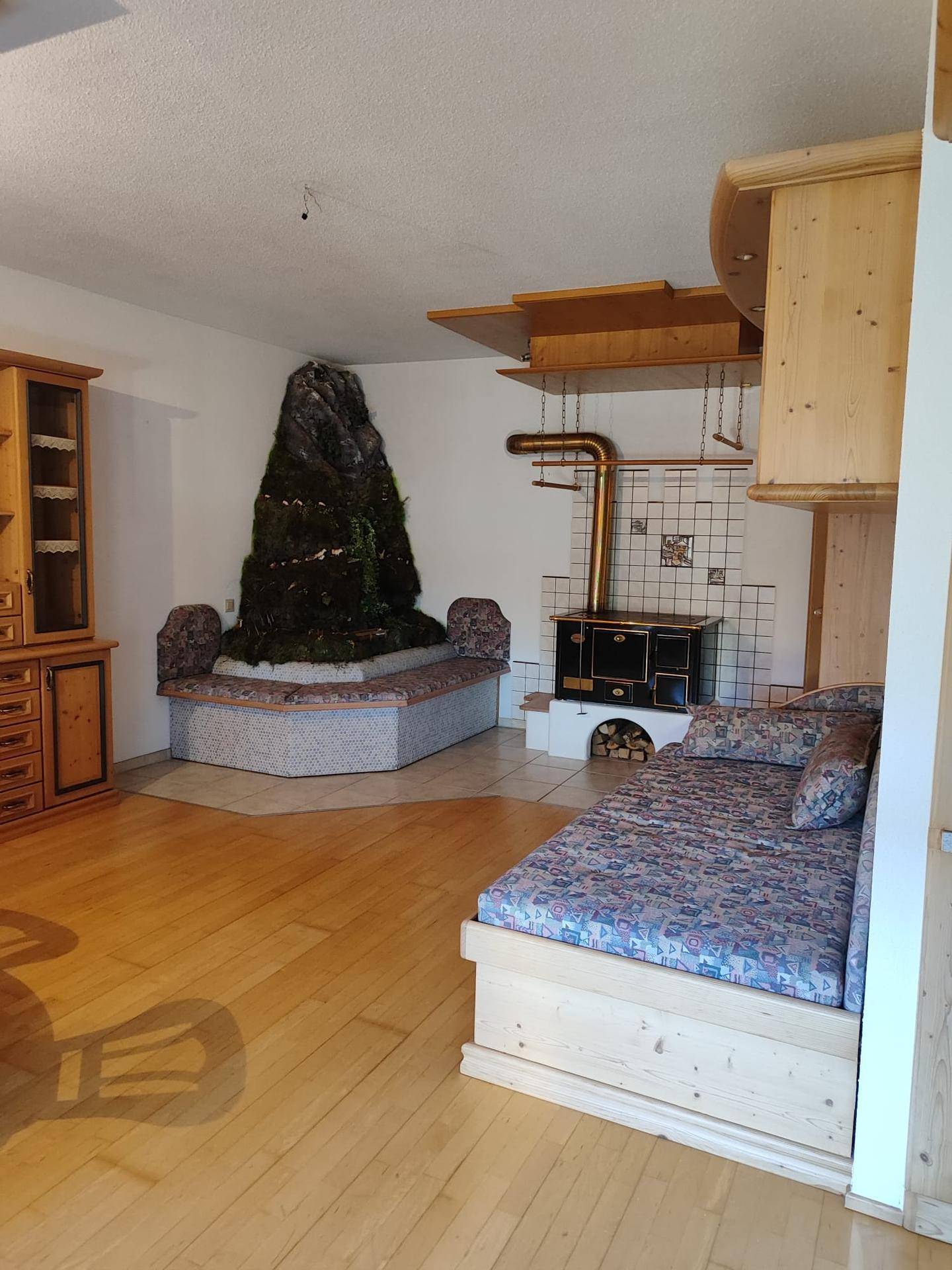 Geräumiges Wohnzimmer mit einzigartigem Fels-Dekorationselement und traditionellem Holzofen.
