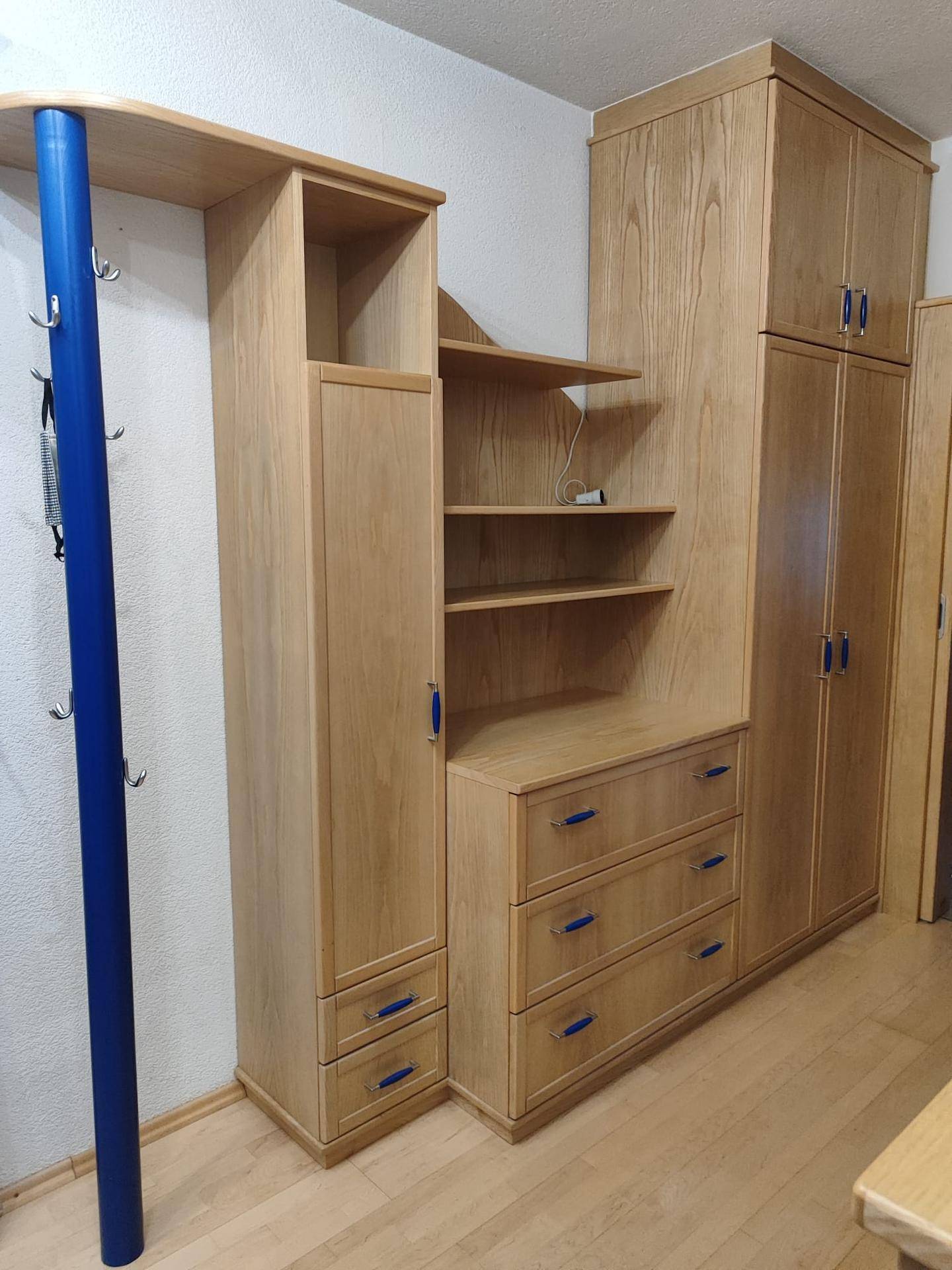 Heller Flur mit Holzmöbeln, Regalen und blauen Akzenten.