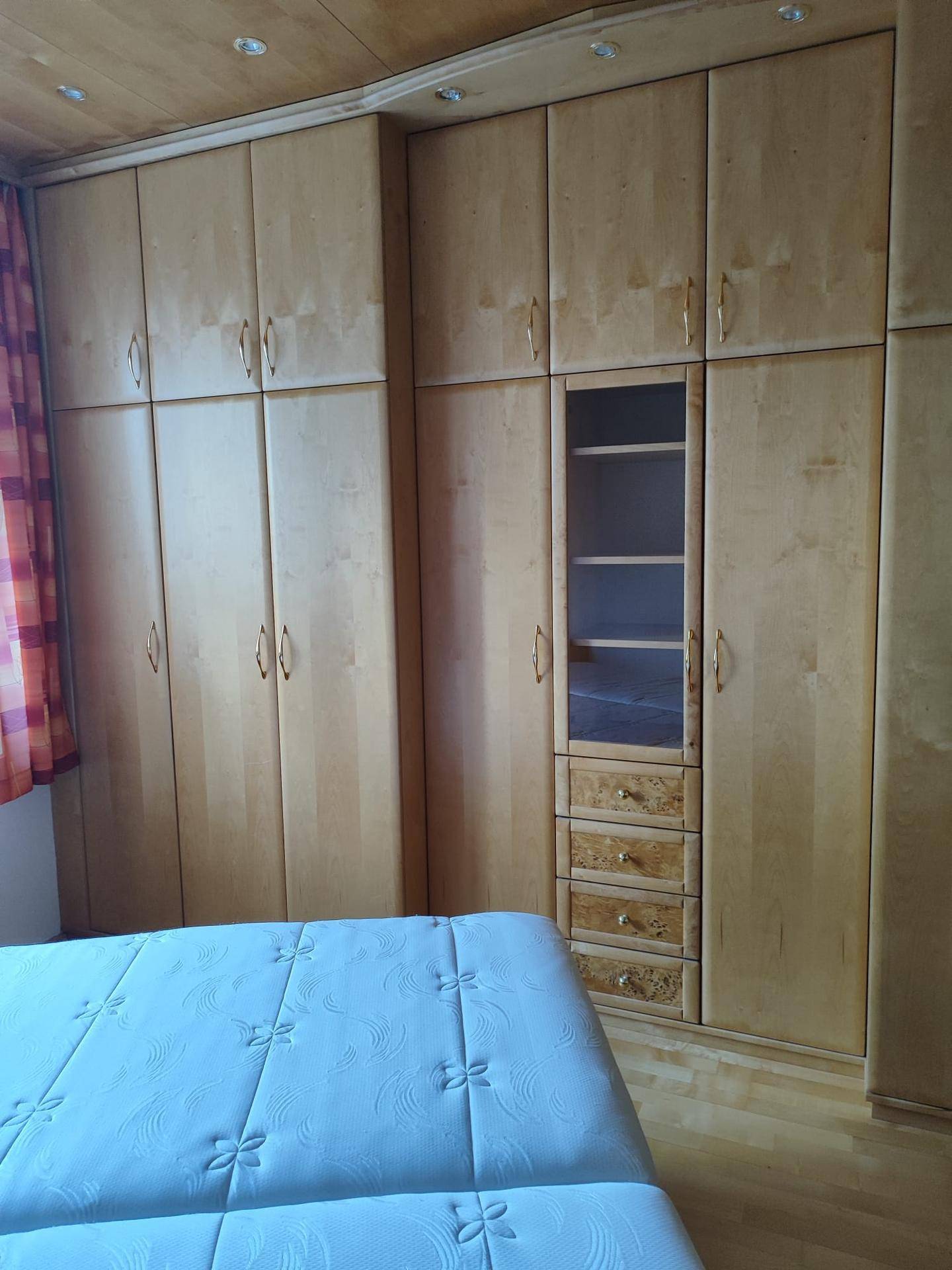 Geräumiger Schlafzimmerschrank aus hellem Holz mit vielen Fächern und Schubladen.