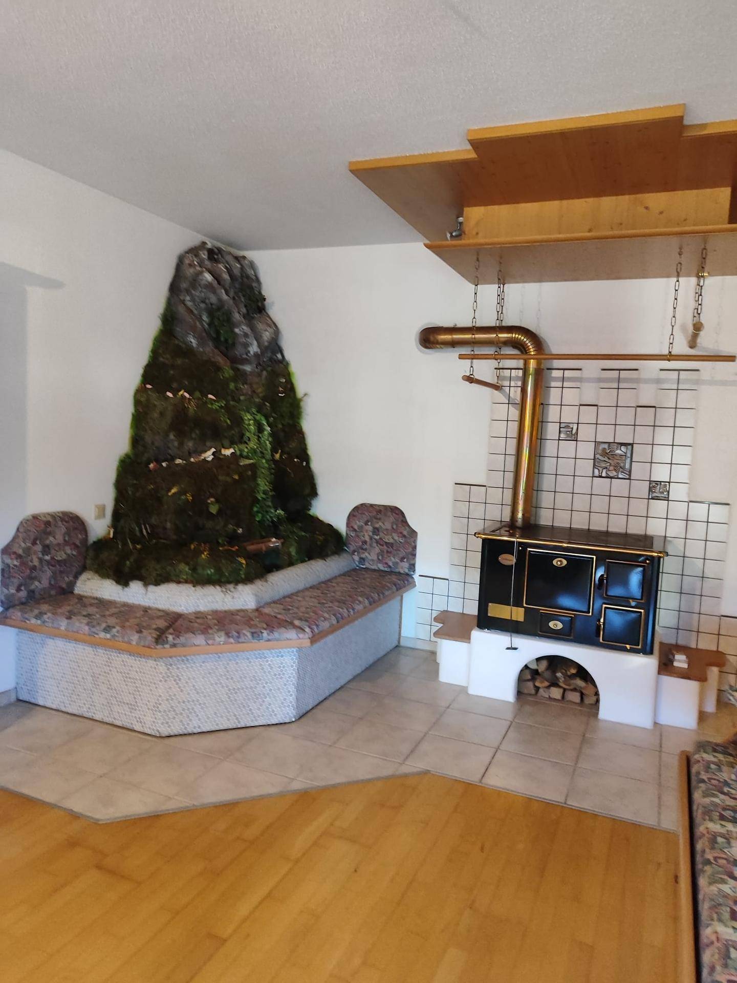 Rustikaler Wohnbereich mit einem dekorativen Felsen, Sitzbank und traditionellem Holzofen.