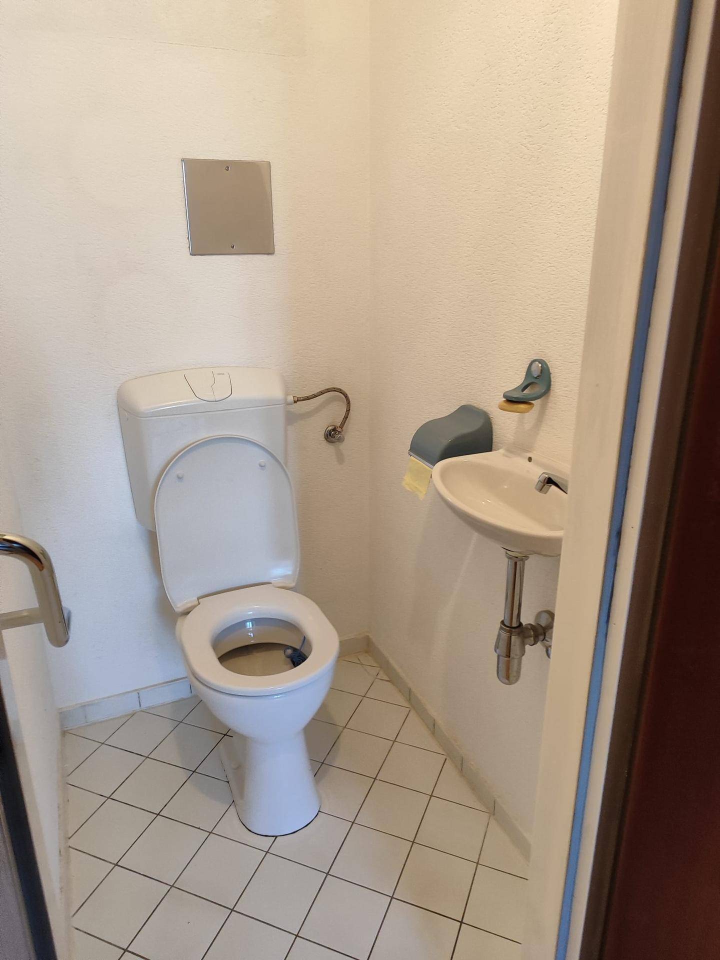 Kleines Gäste-WC mit Toilette, Waschbecken und Fliesenboden.
